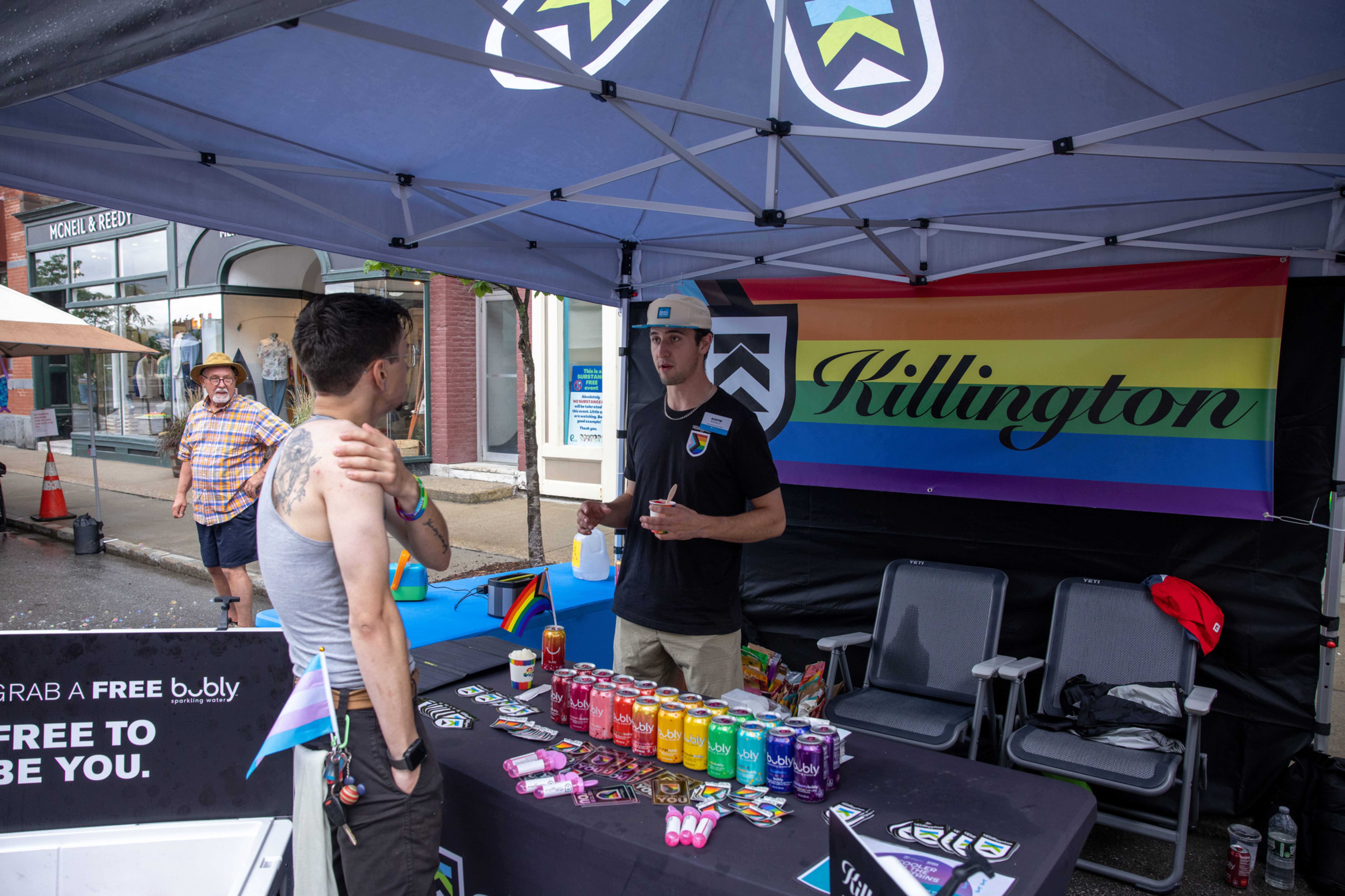 People at a tent promoting Killington, with colorful beverages and a rainbow flag backdrop.