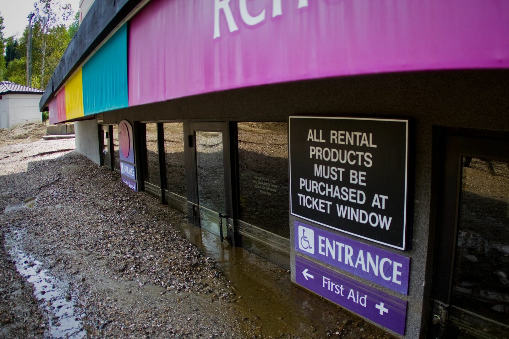 Signage for rental products, entrance, and first aid at a ticket window location.