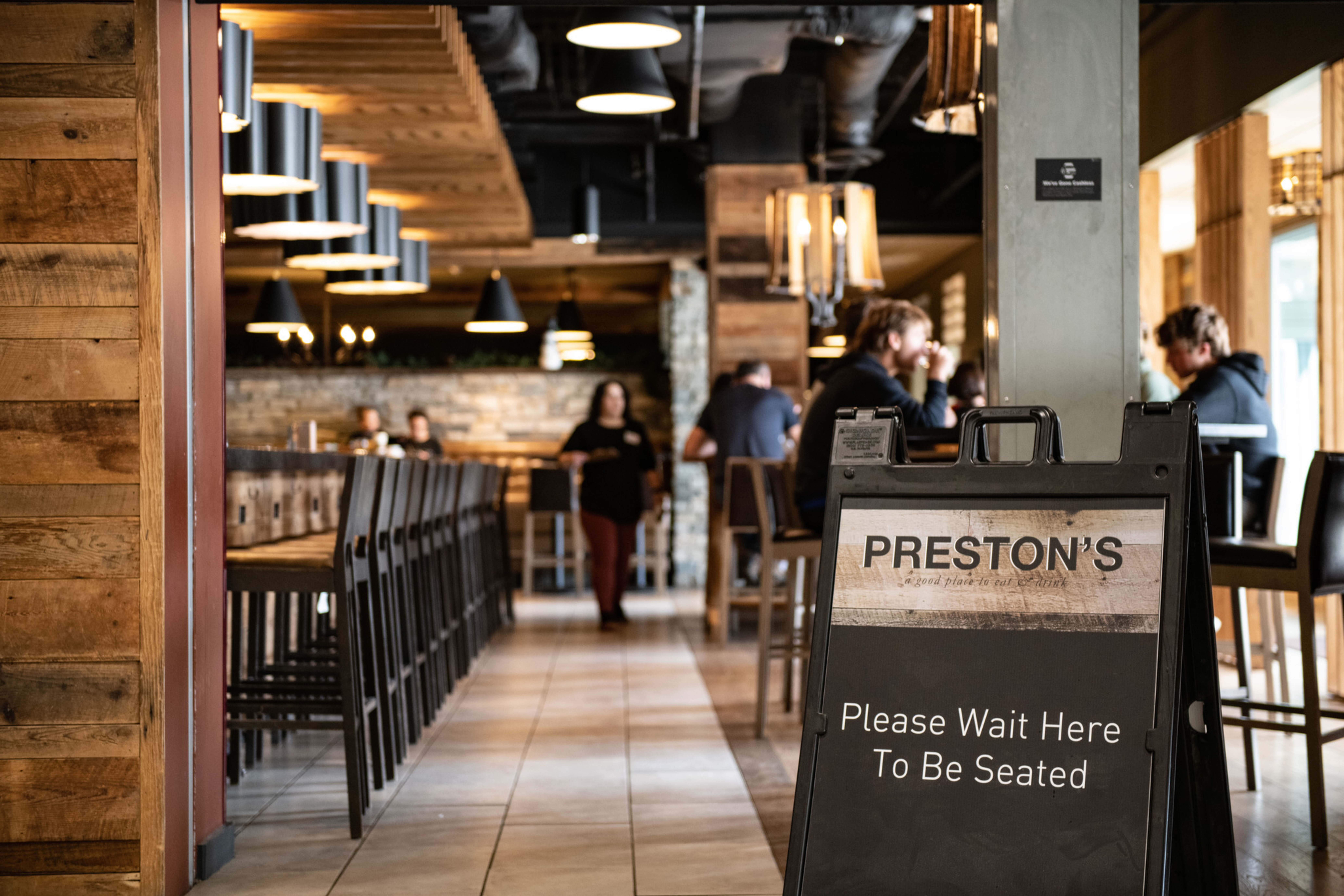 Modern restaurant interior with a waiting sign at Preston's.