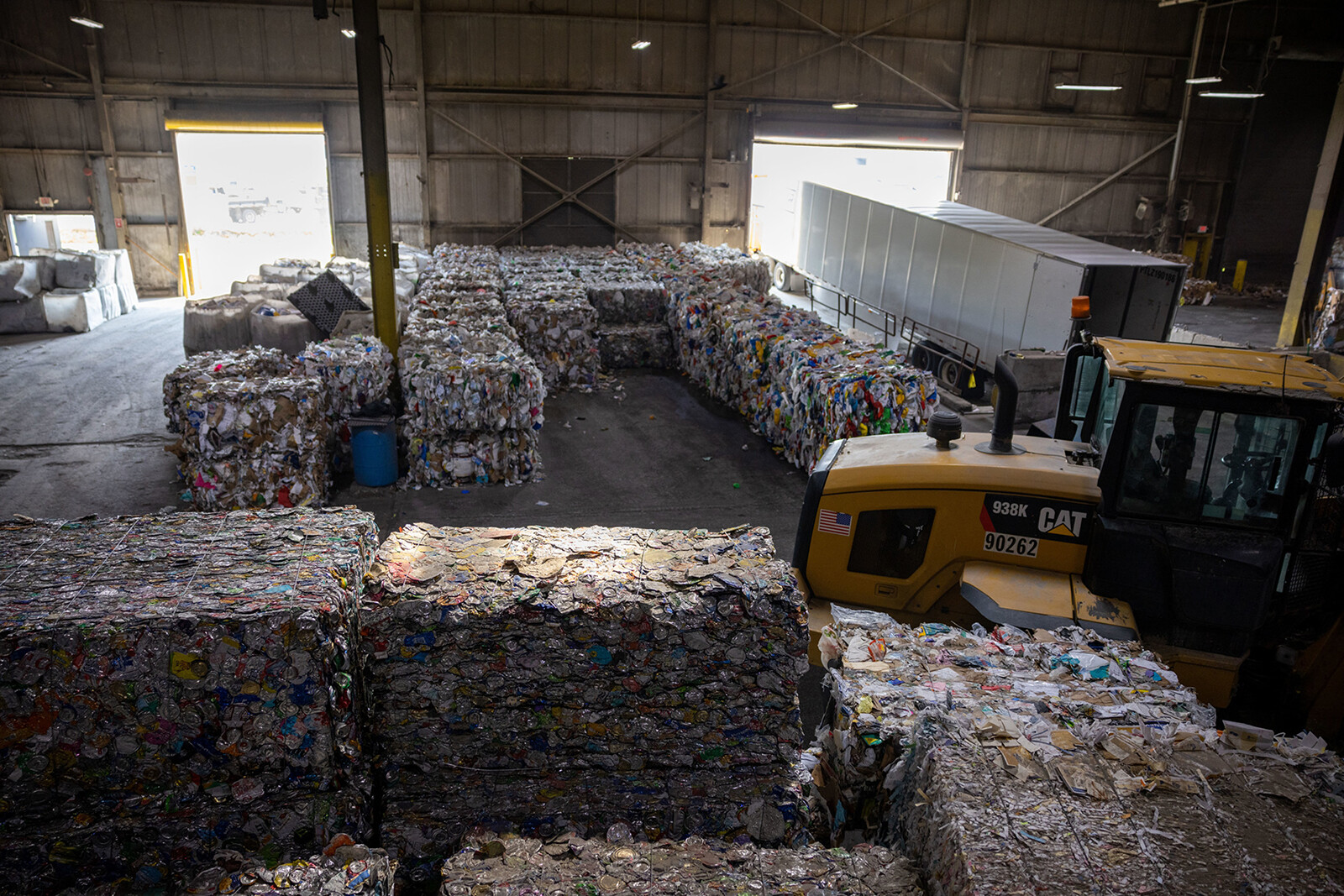 View of a recycling facility with large bales of sorted materials and heavy machinery.