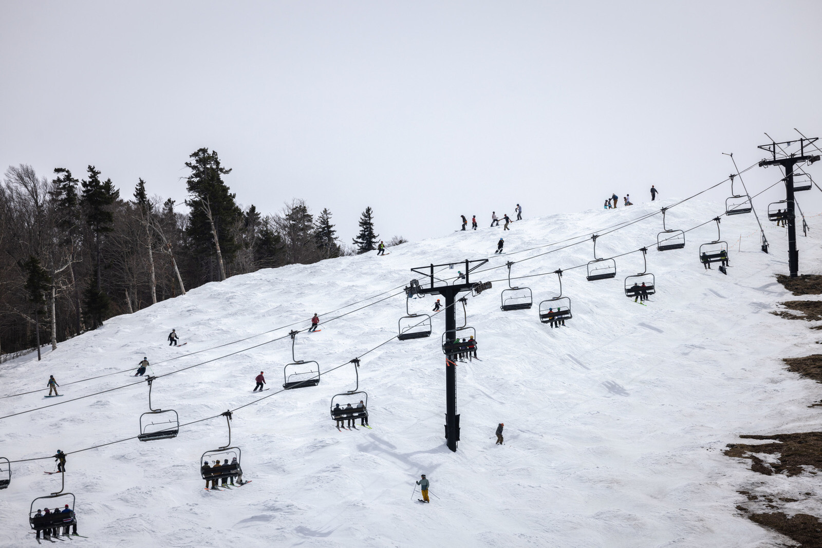 Skiers navigate a snowy slope with a ski lift in the foreground.