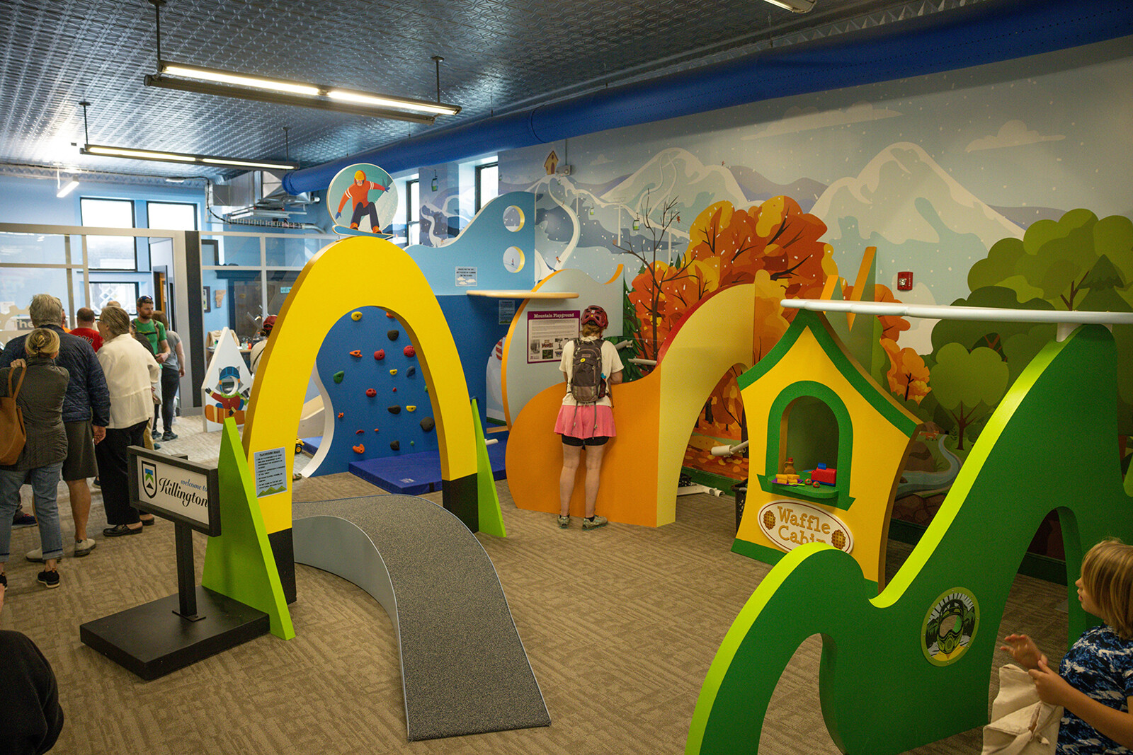 Colorful indoor play area with climbing structures and playful murals, featuring children exploring.