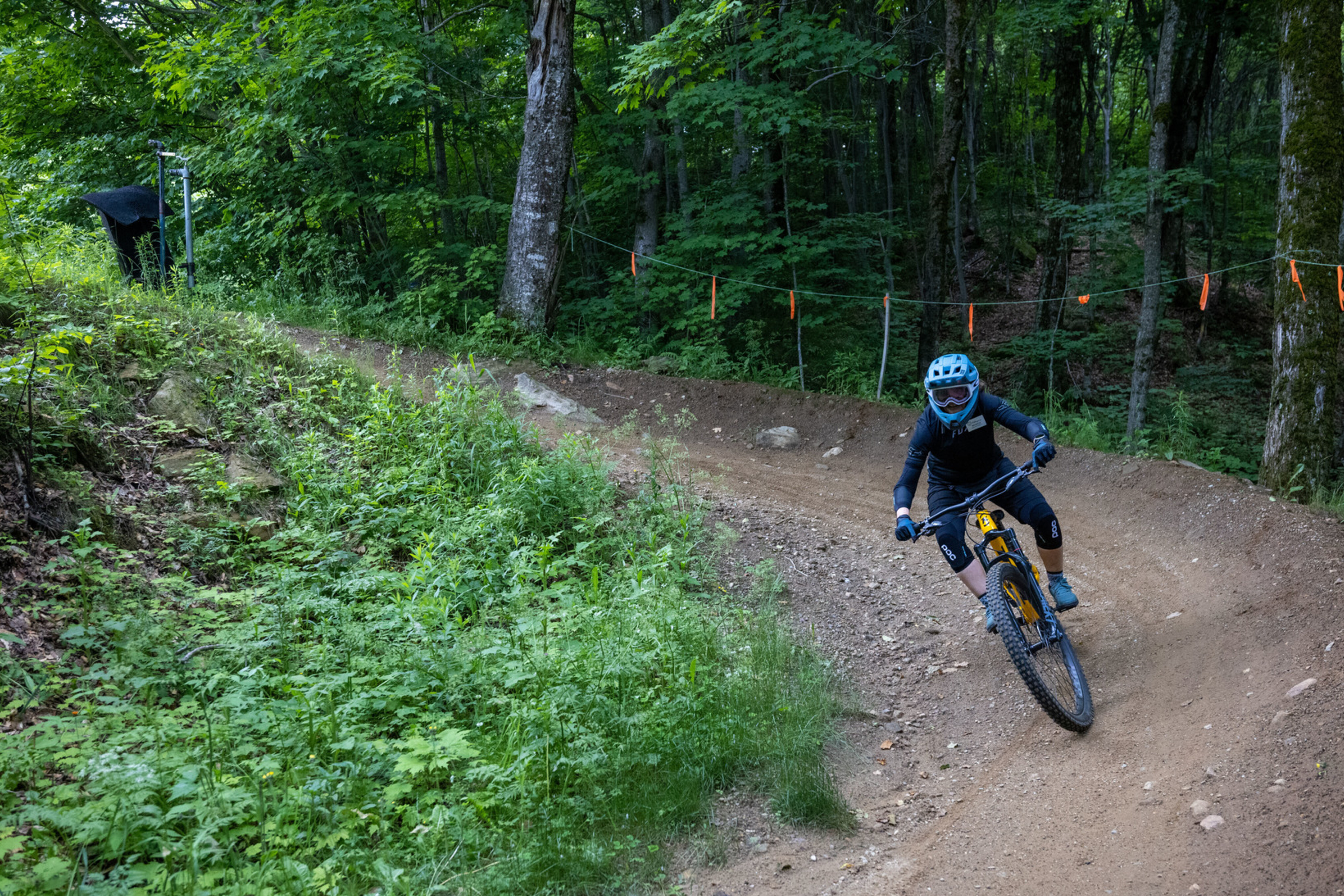 A mountain biker navigates a curvy trail in a lush forest setting.