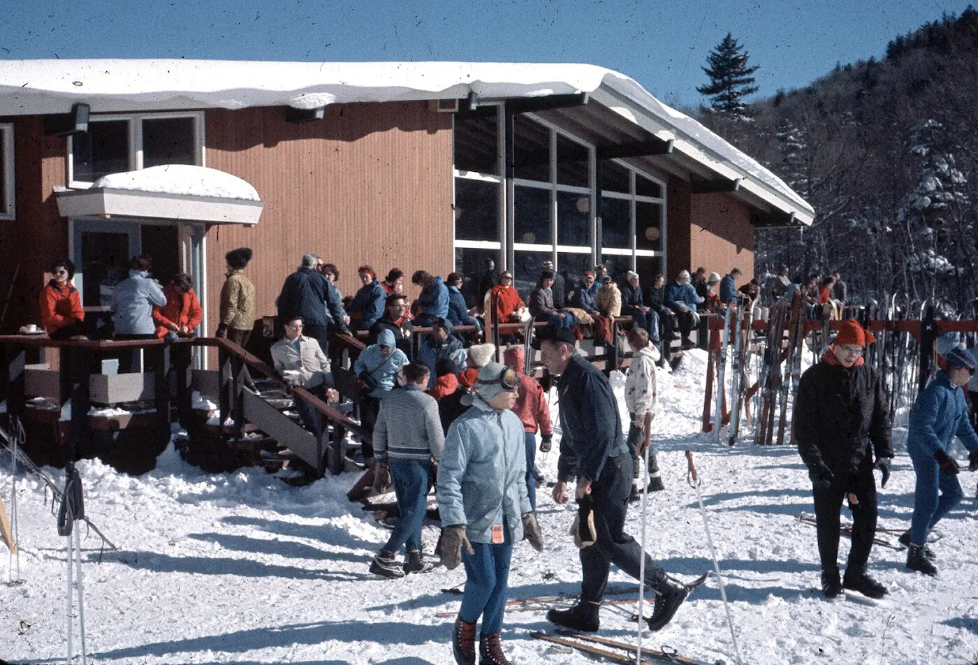 Skiers and visitors gathering outside a lodge on a snowy mountain.