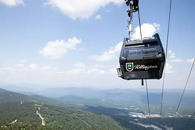 A Killington gondola aerially views green mountains and blue skies.