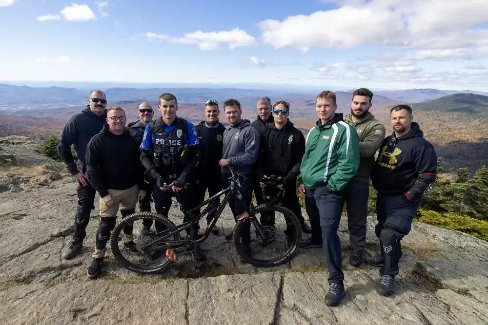 Group of mountain bikers posing on a rocky peak with scenic landscape behind.