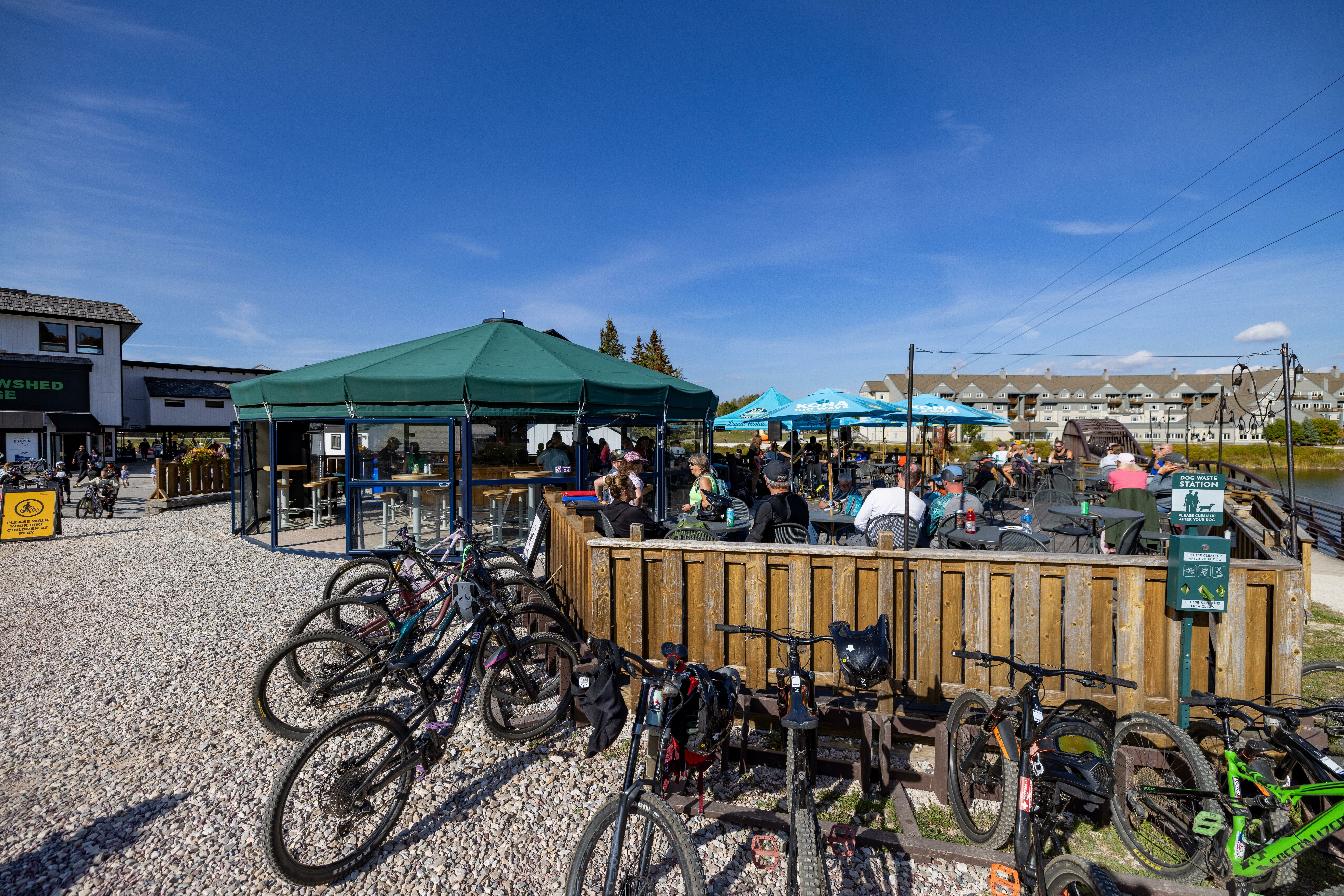 Bikes parked near a bustling outdoor caf&eacute; with patrons enjoying the sunny weather.