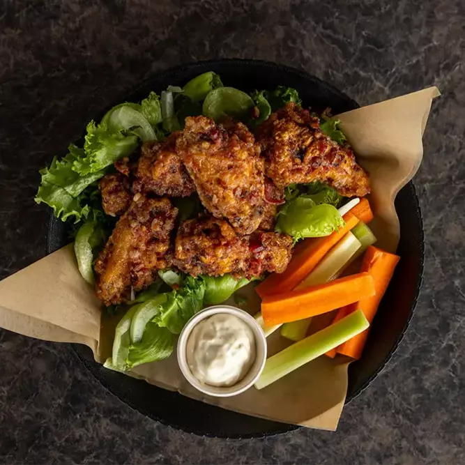 Crispy chicken wings on lettuce, with celery, carrots, and dipping sauce.