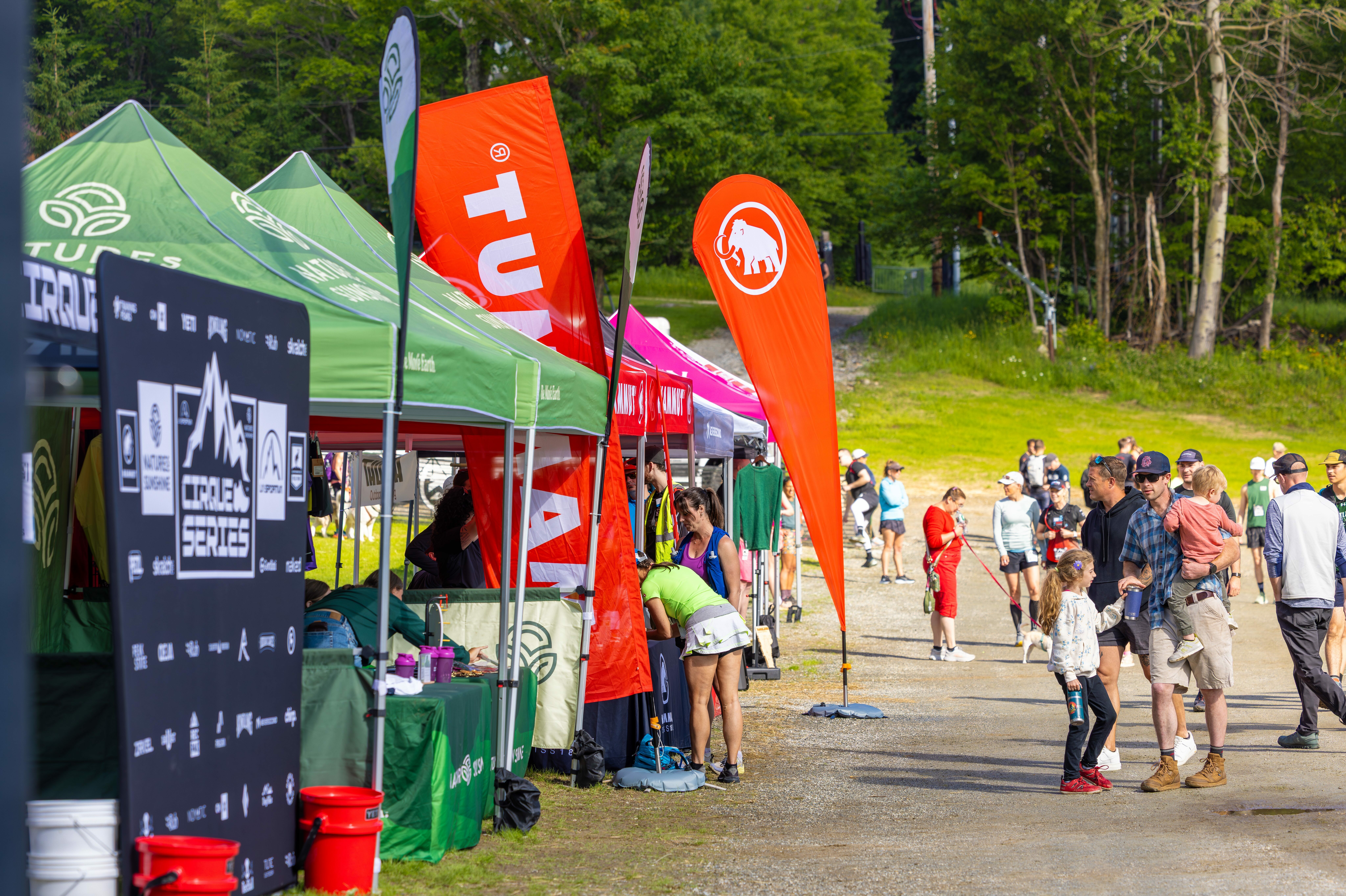 Crowd gathering at a lively outdoor event with vendor tents and colorful flags