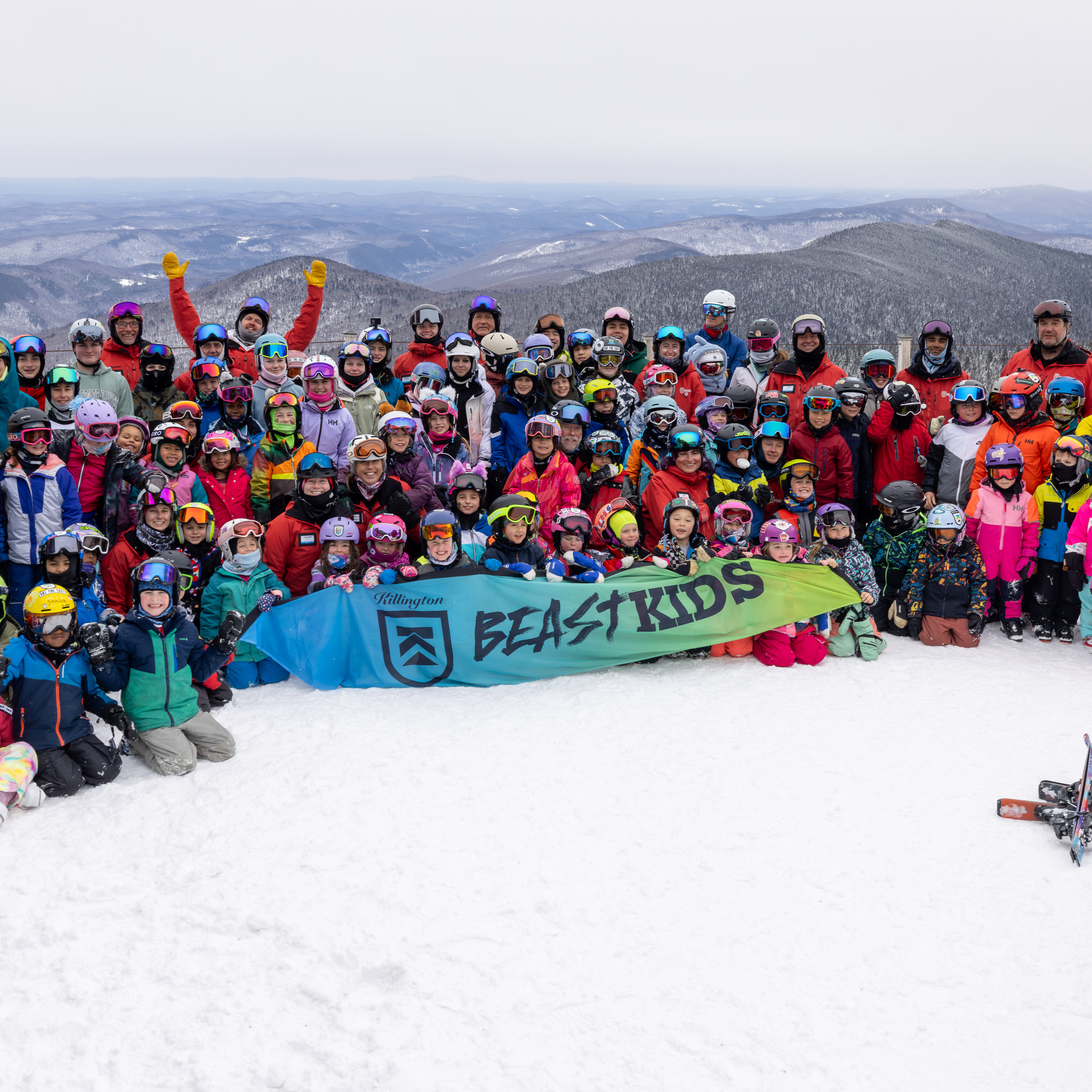 Group photo of kids and instructors at a ski event, holding a "Beast Kids" banner.