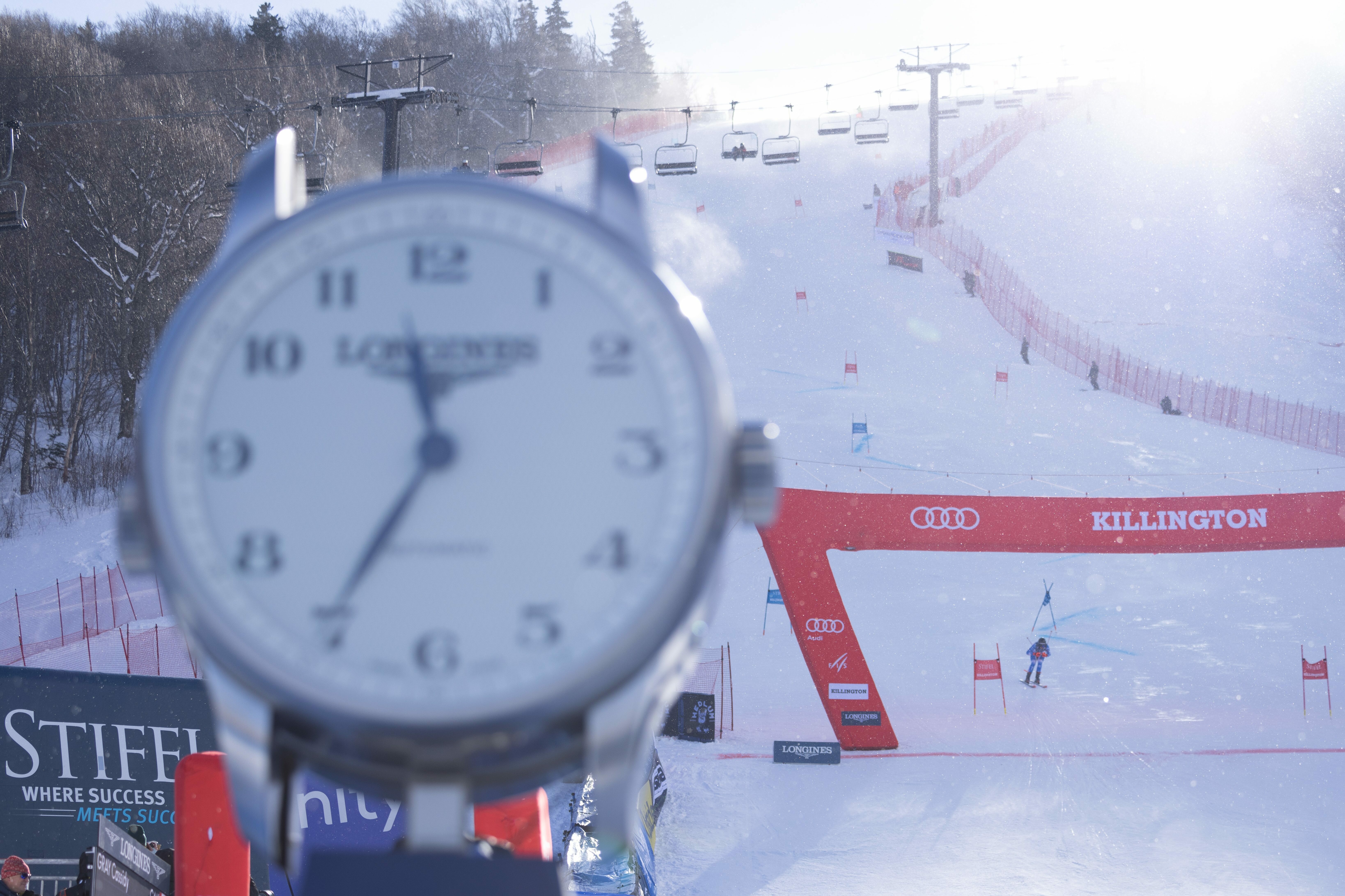 A watch in focus with a snowy ski slope and race gates in the background at Killington.