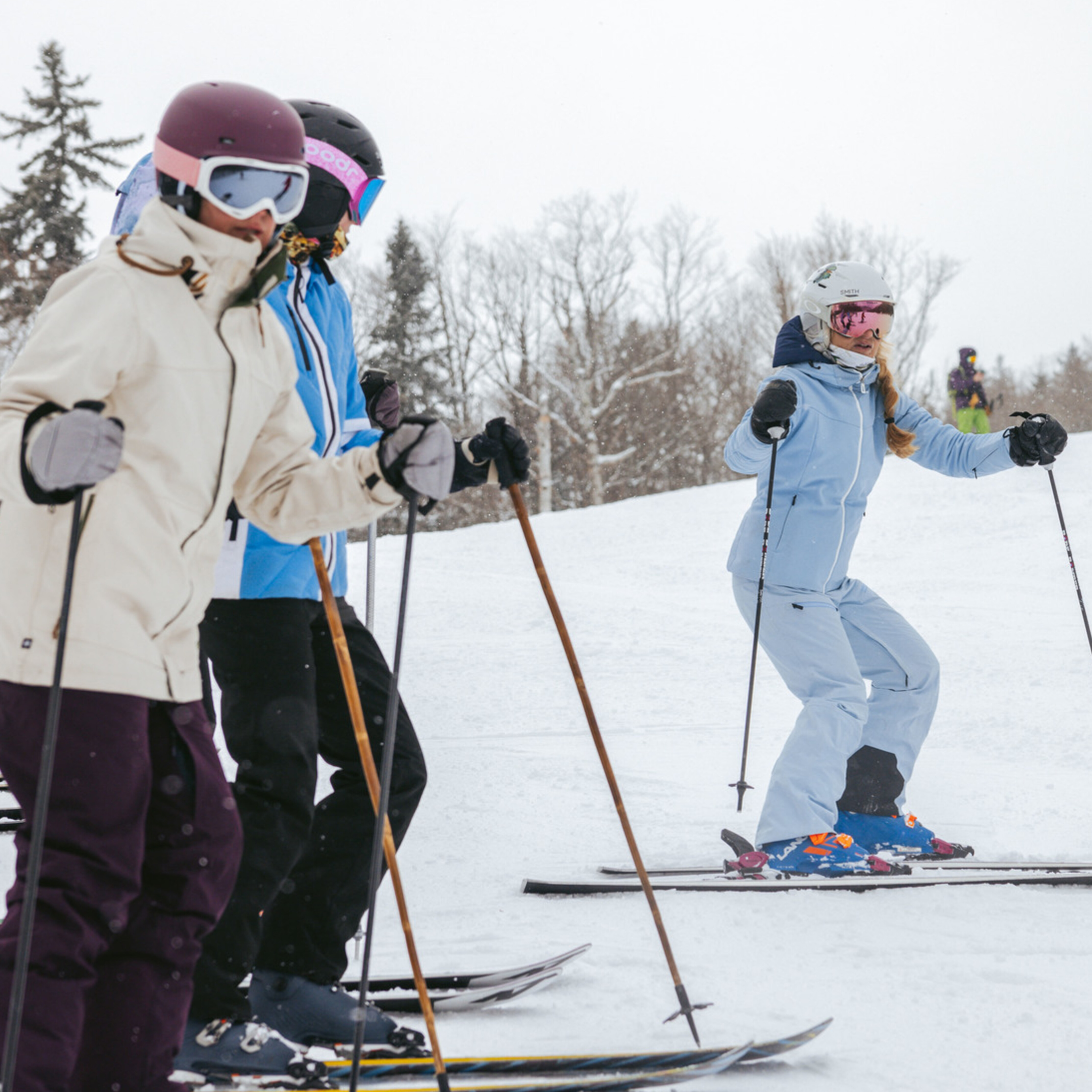 Four skiers in winter gear practice skiing on a snowy slope.