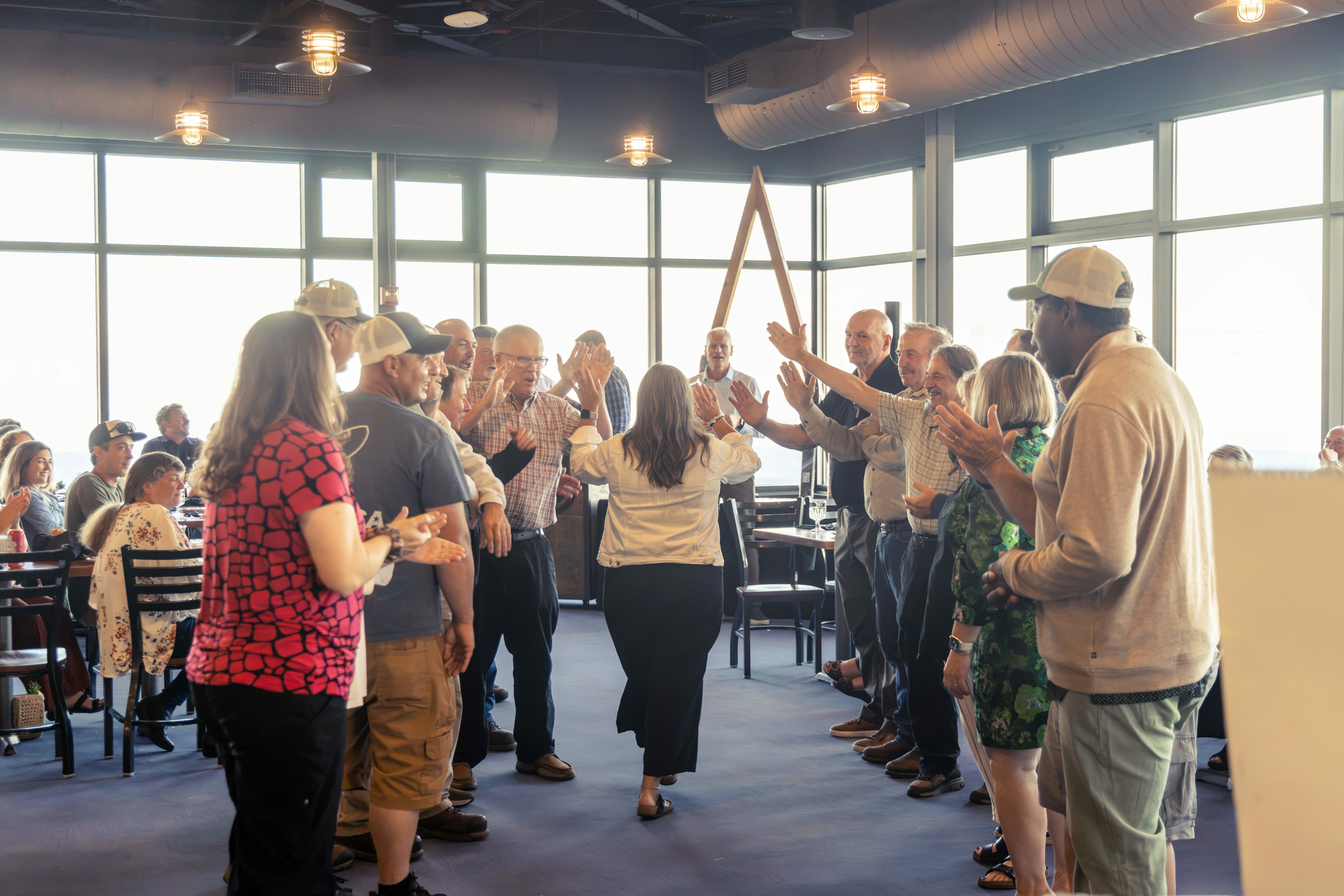 A crowd claps as a woman walks through an applauding line.