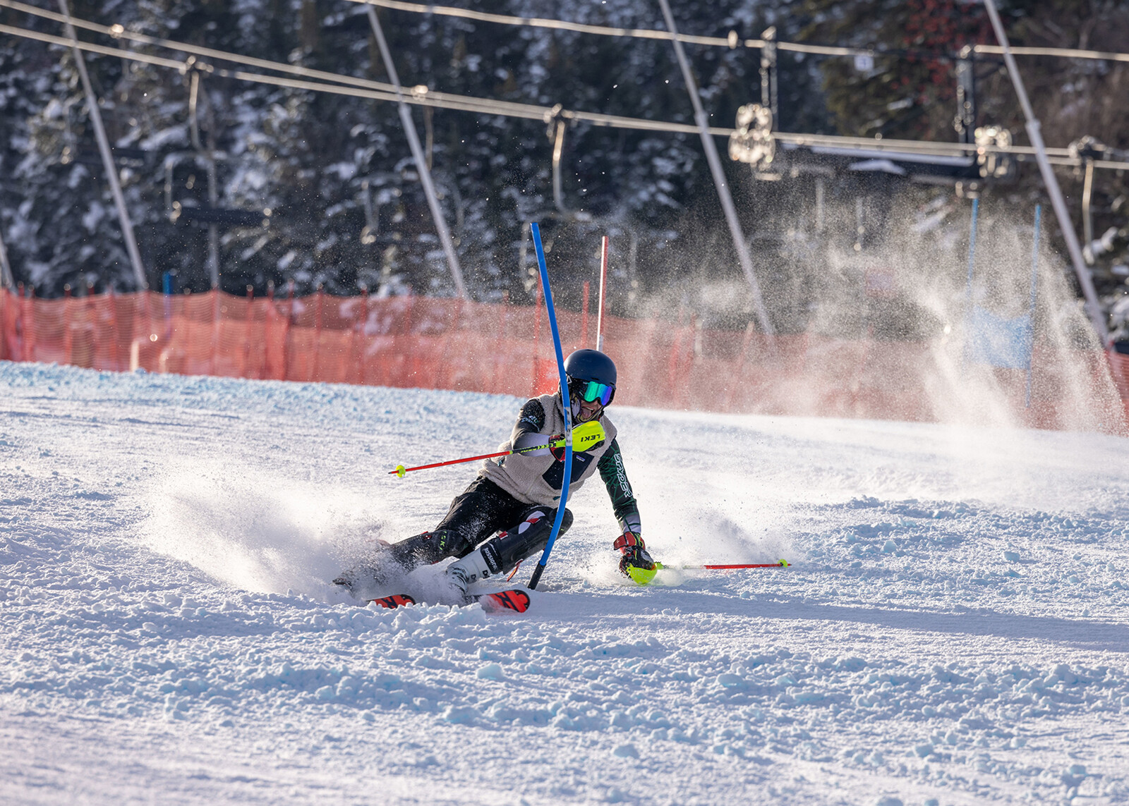 Skier navigating a slalom course, kicking up snow in a winter landscape.