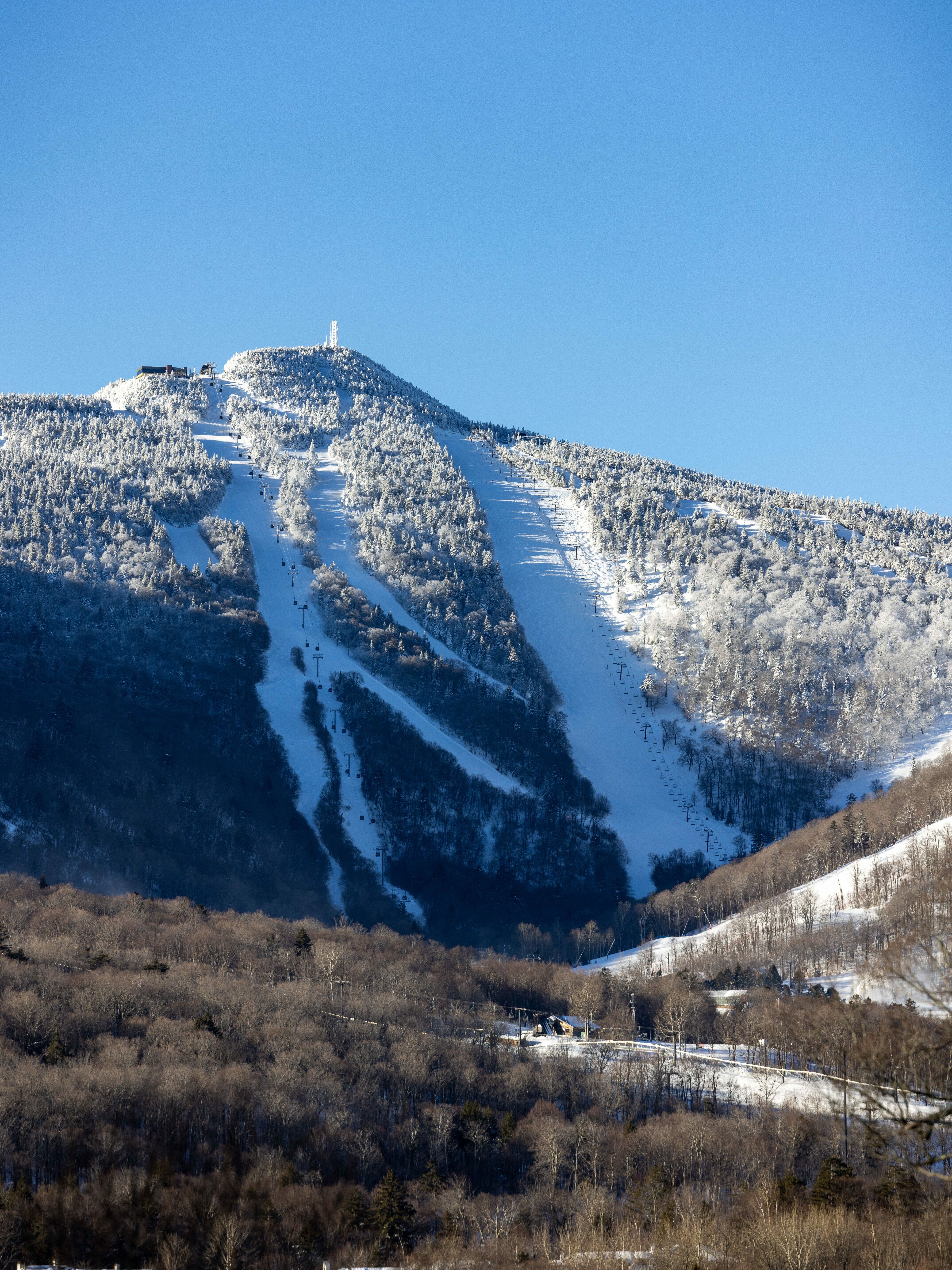 Snow-covered mountain peak with ski slopes and a clear blue sky.