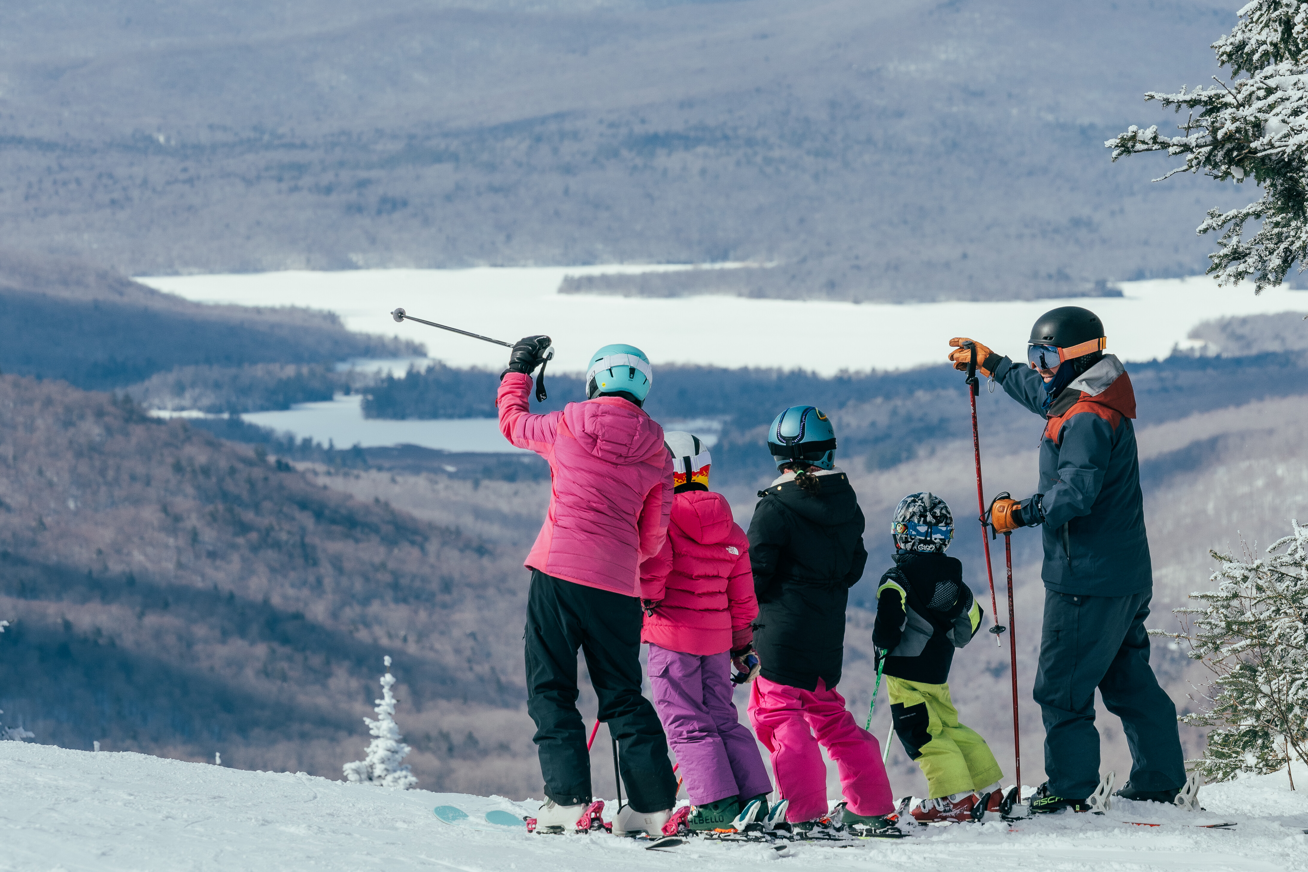 A group of skiers overlooking a snowy landscape from a mountain summit.