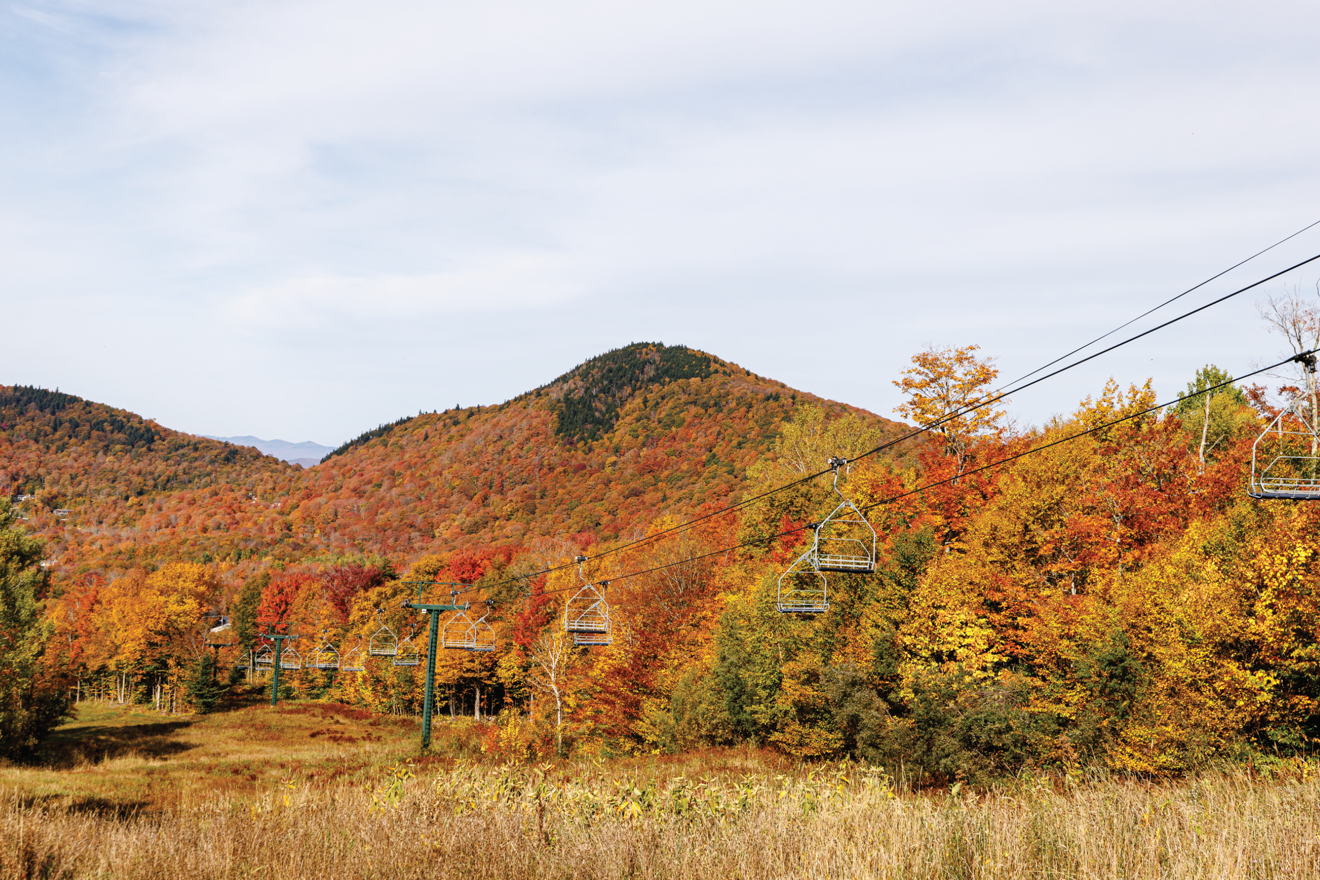 Colorful autumn foliage surrounds a ski lift in the mountains.
