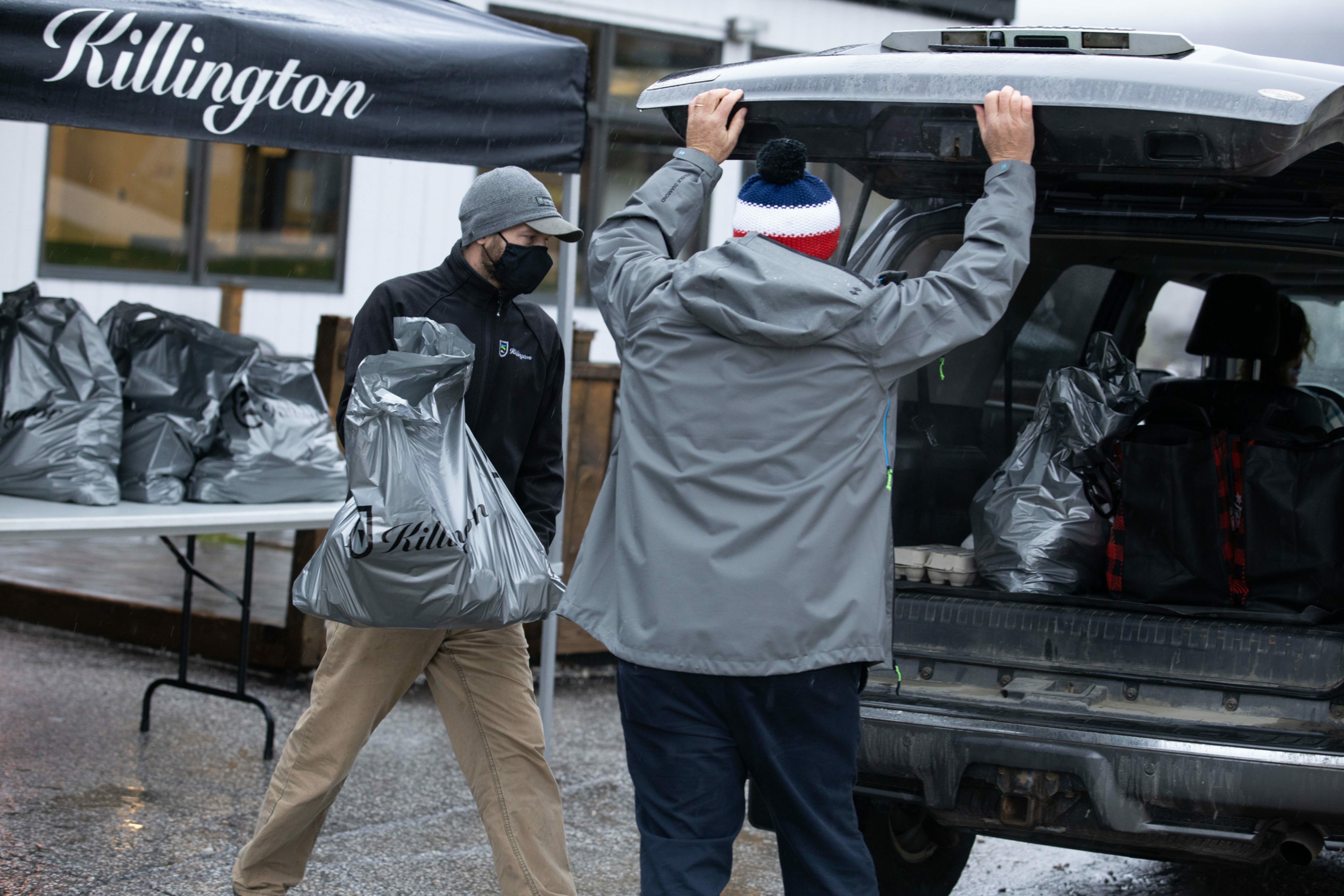 Two men drop groceries off in the back of a vehicle during a food drive at Killington Resort.