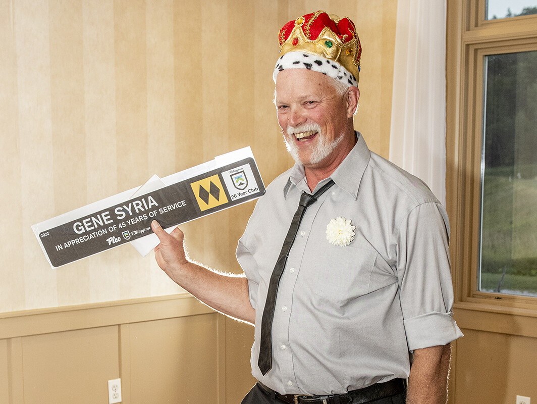 Man in a crown holding a sign recognizing 45 years of service.