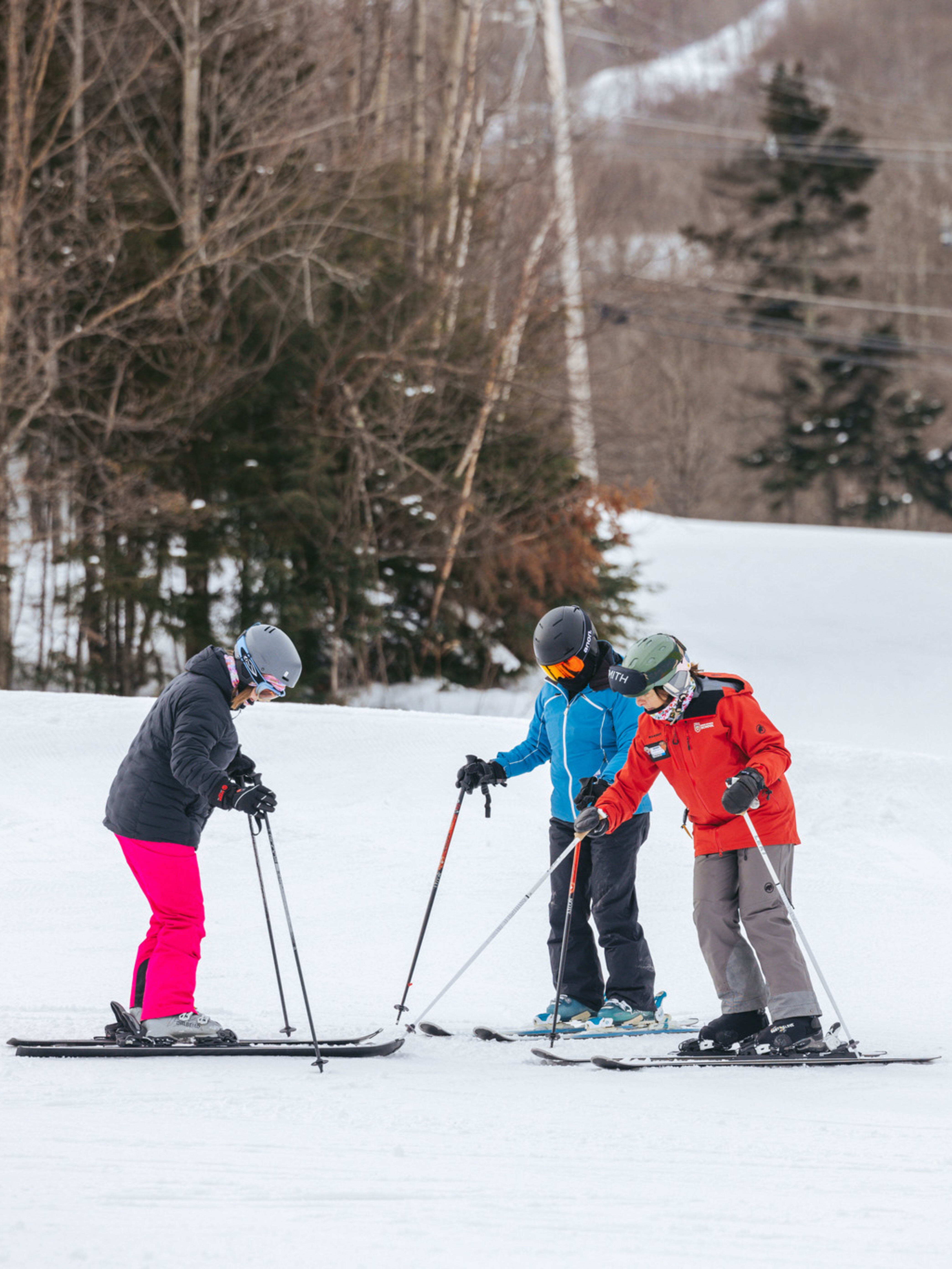 Three skiers, two women and a man, practice on a snowy slope in winter gear.