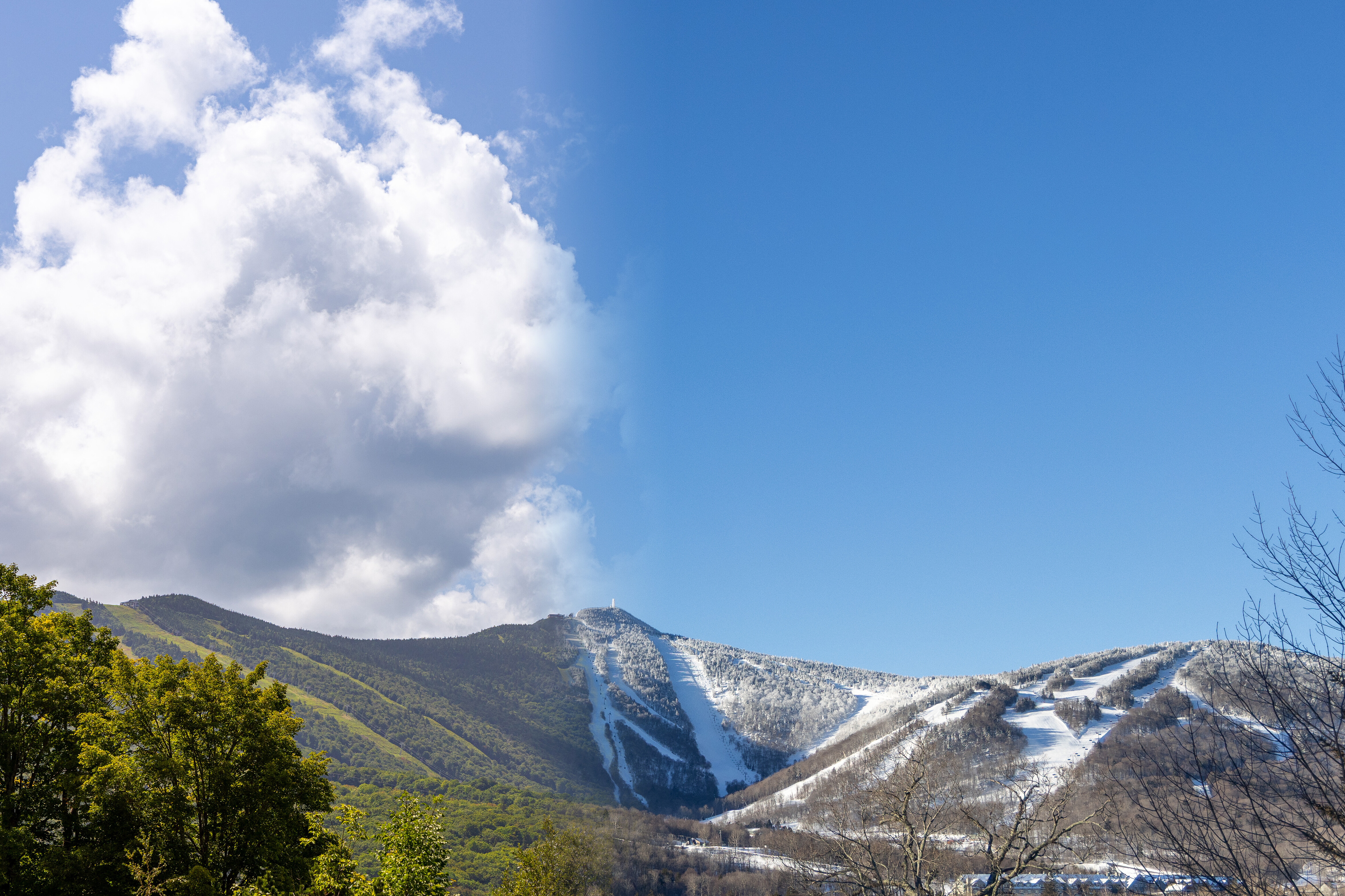 Split image of a green mountain under clouds and a snow-covered slope under a clear blue sky.