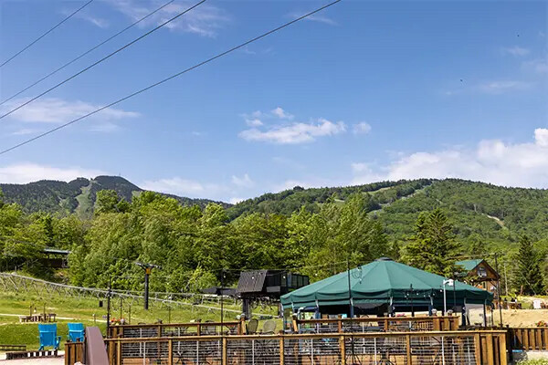Scenic view of green hills under a blue sky with a tent and buildings in the foreground.