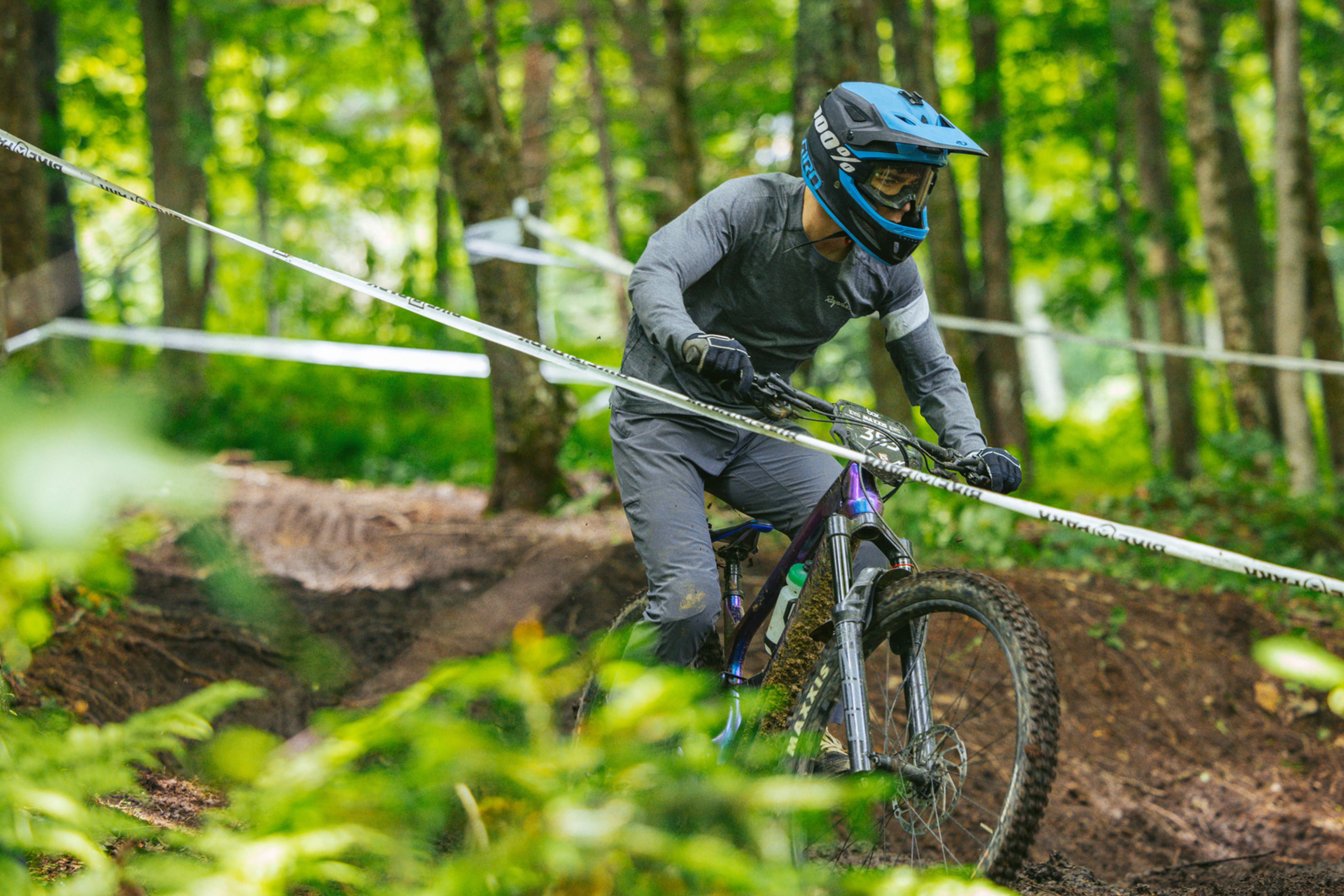 A mountain biker navigates a steep trail in a lush forest.