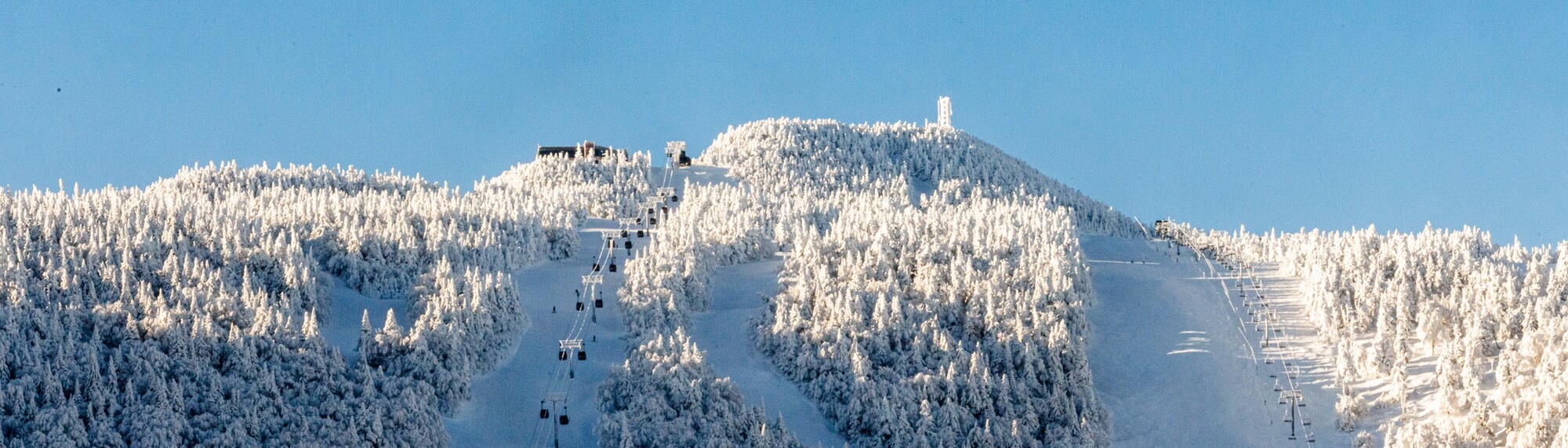 Snow-covered mountains with ski lifts and blue sky.