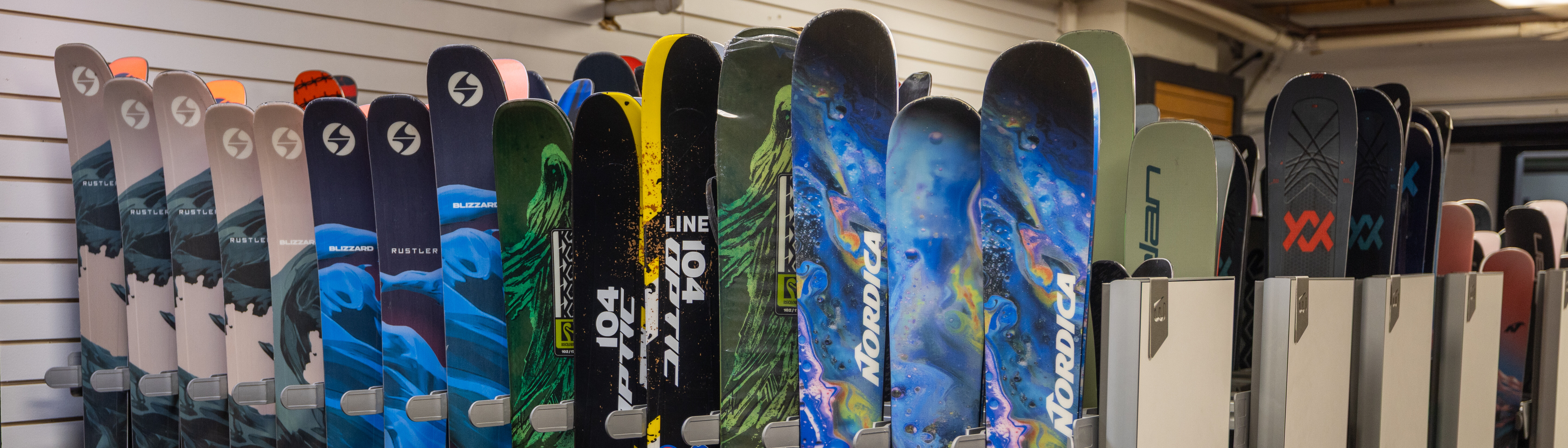 Row of colorful skis displayed on a rack in a sporting goods store.