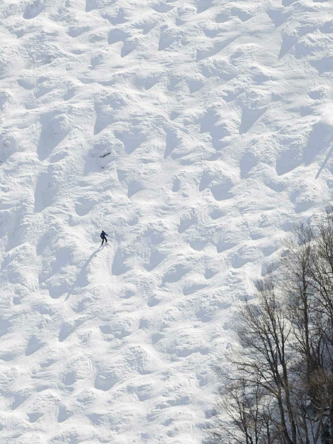 A lone skier traverses a snowy landscape with textured patterns.