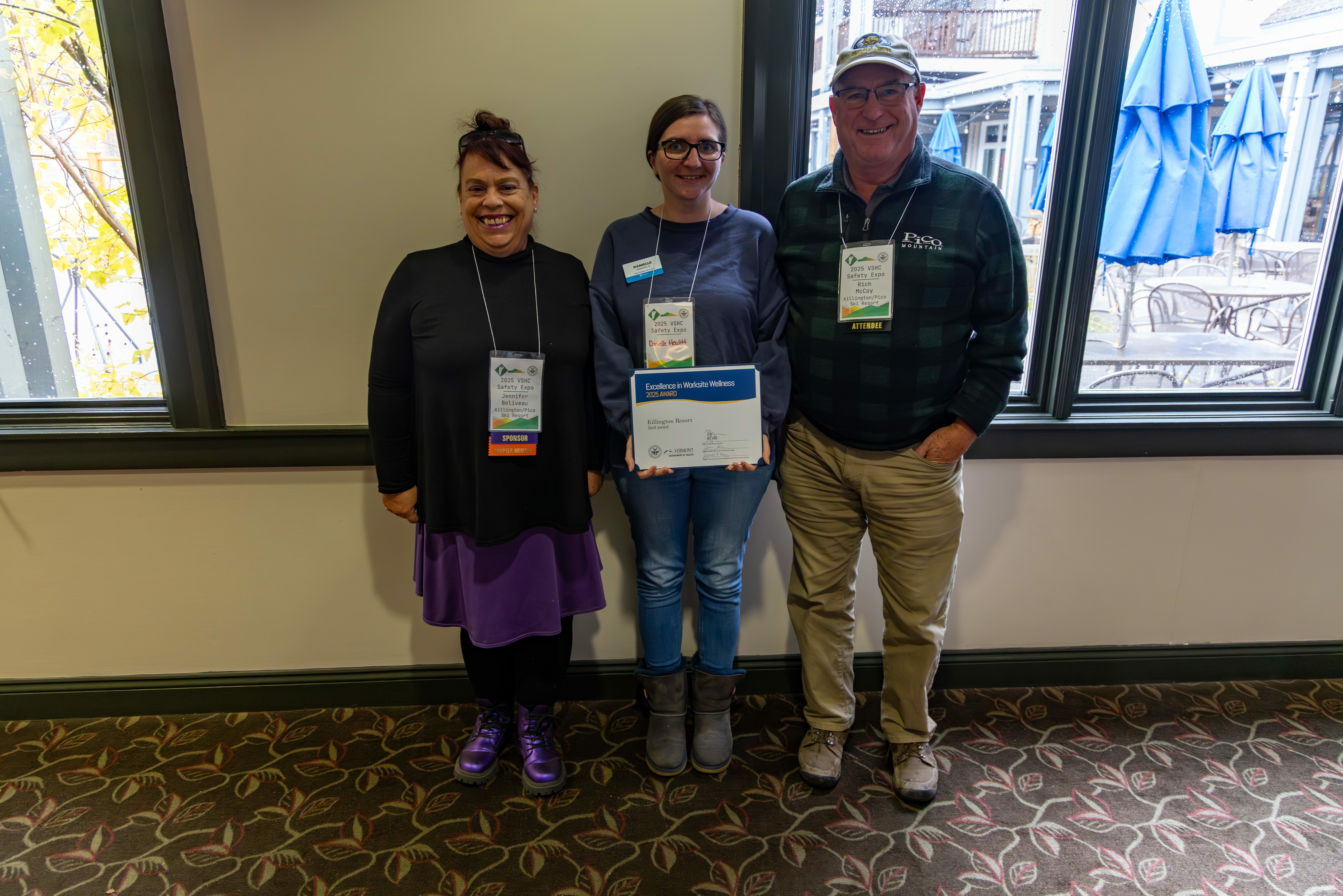Three people stand together holding an award for Excellence in Workplace Wellness.