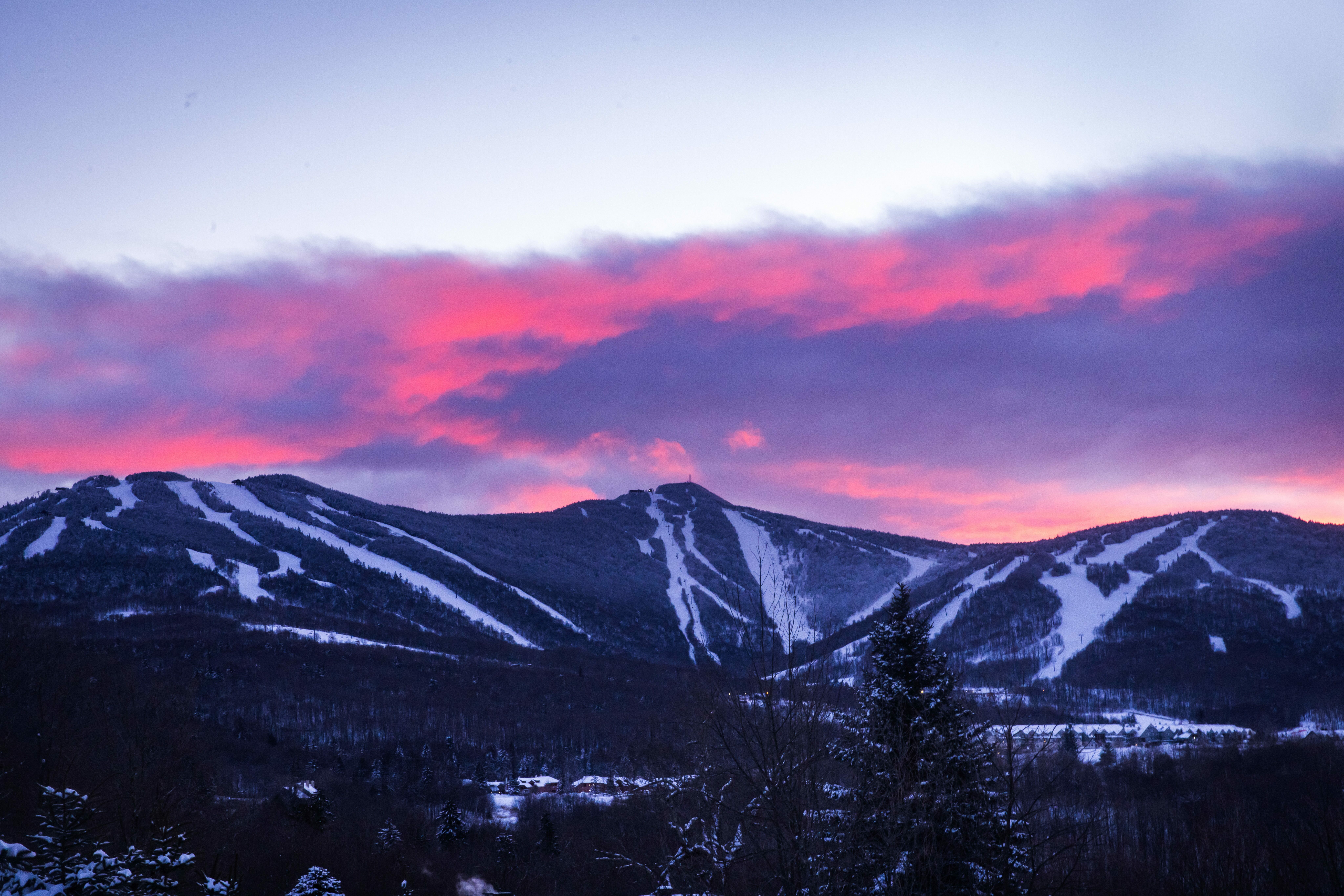 Snow-covered mountains rise under a vibrant pink and purple sunset.
