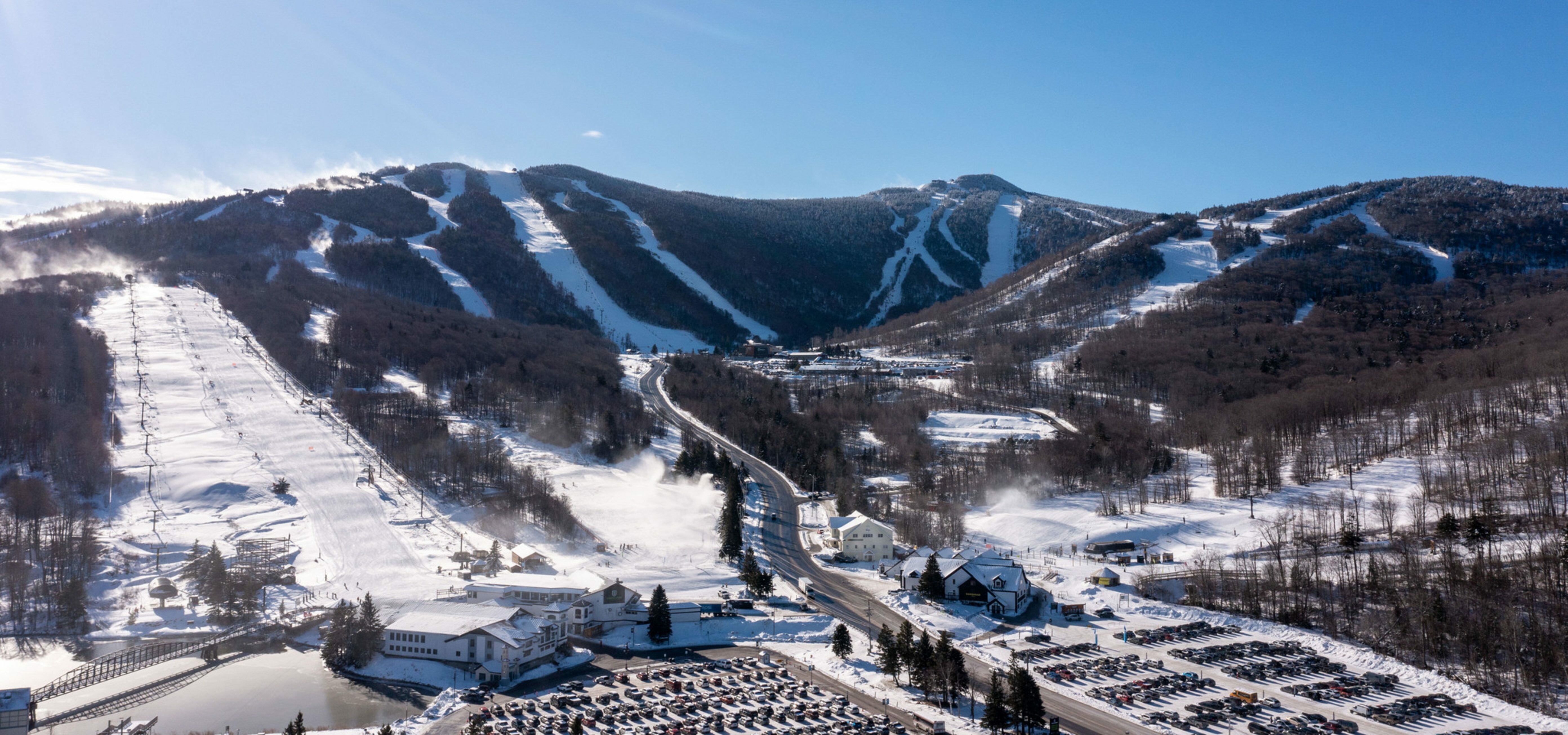 A snowy mountain landscape with ski slopes and a bustling ski resort below.