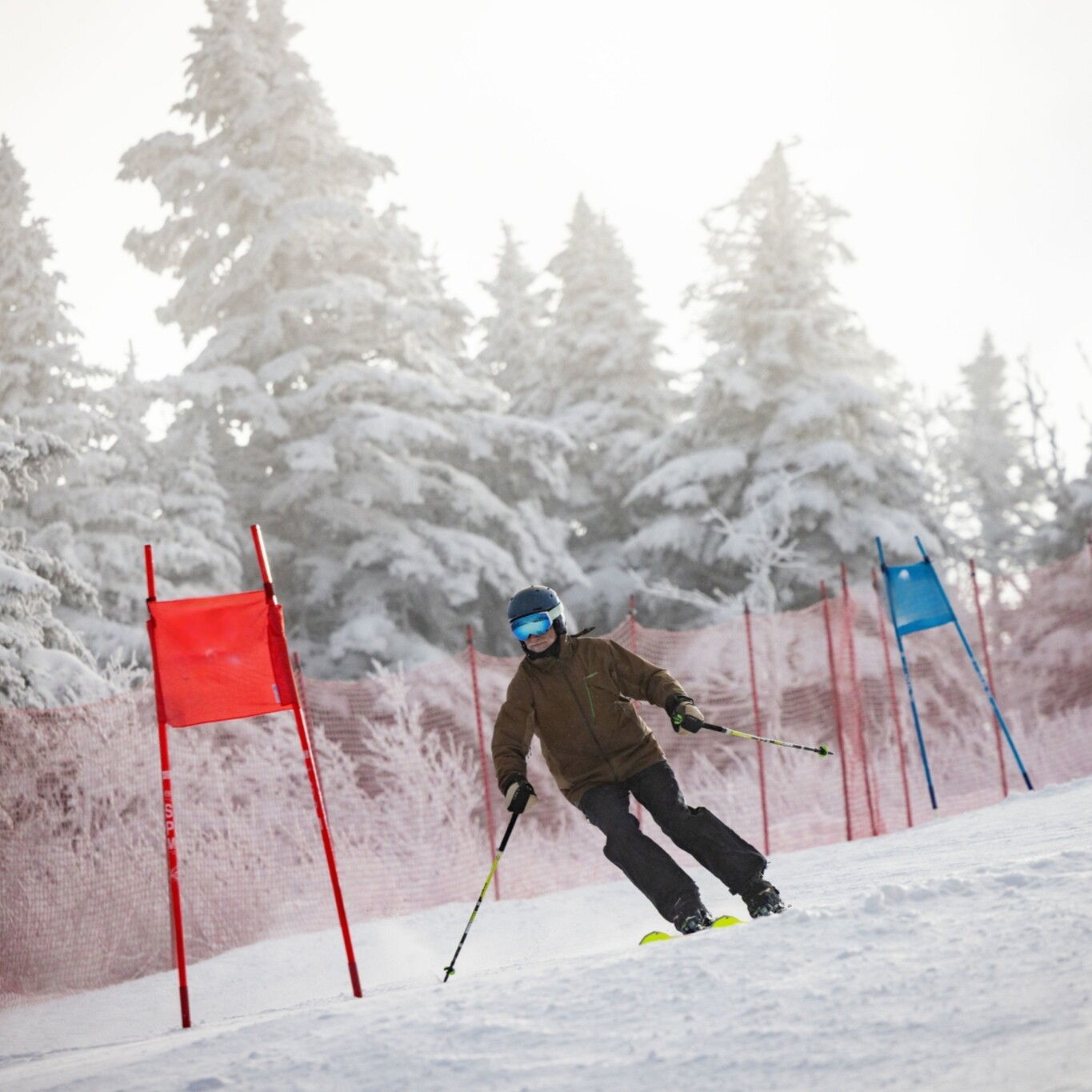 Skier navigating a snowy slope with red and blue flags in the background.