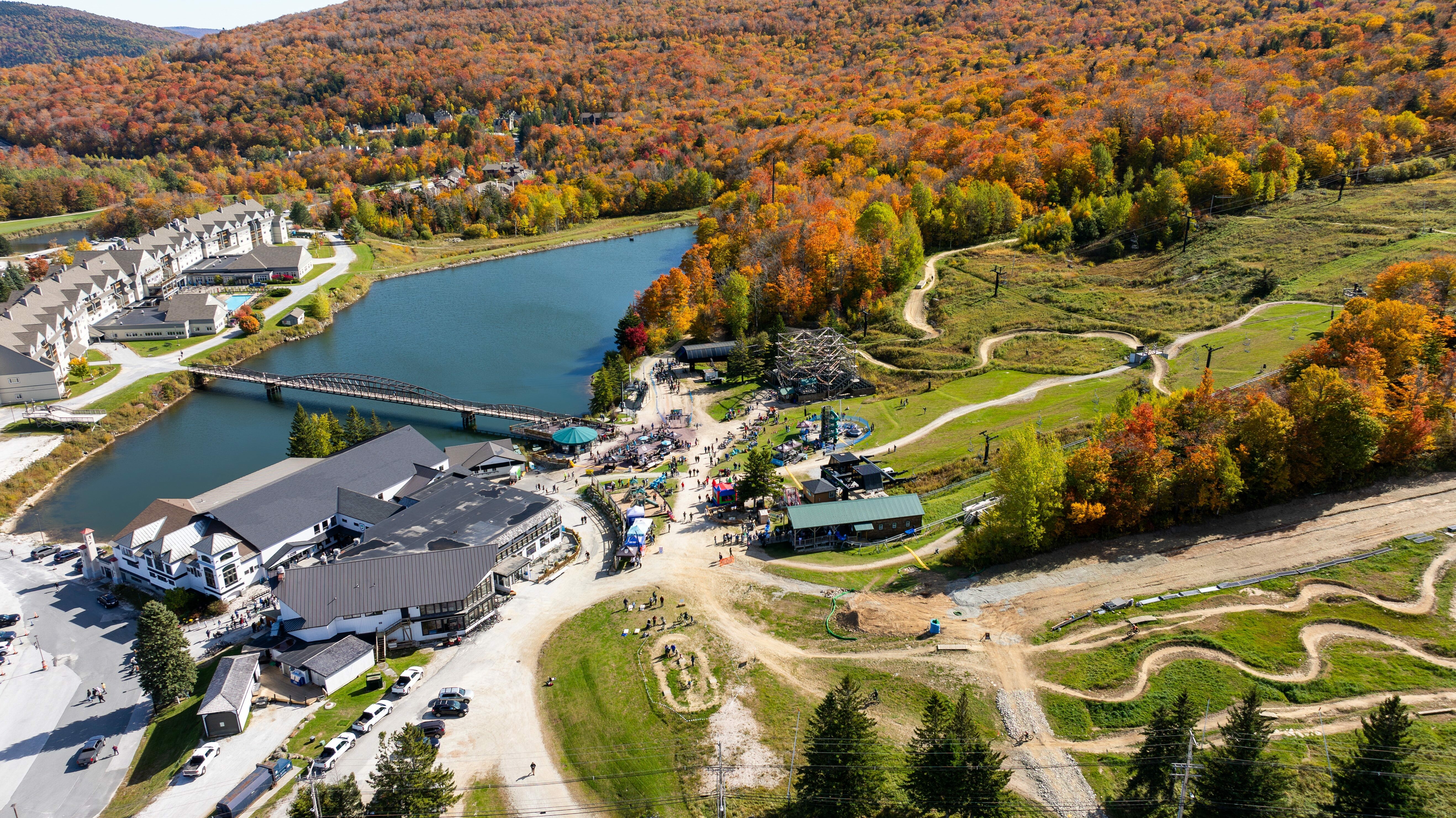 Aerial view of a resort area with vibrant fall foliage, pond, and activity spaces.