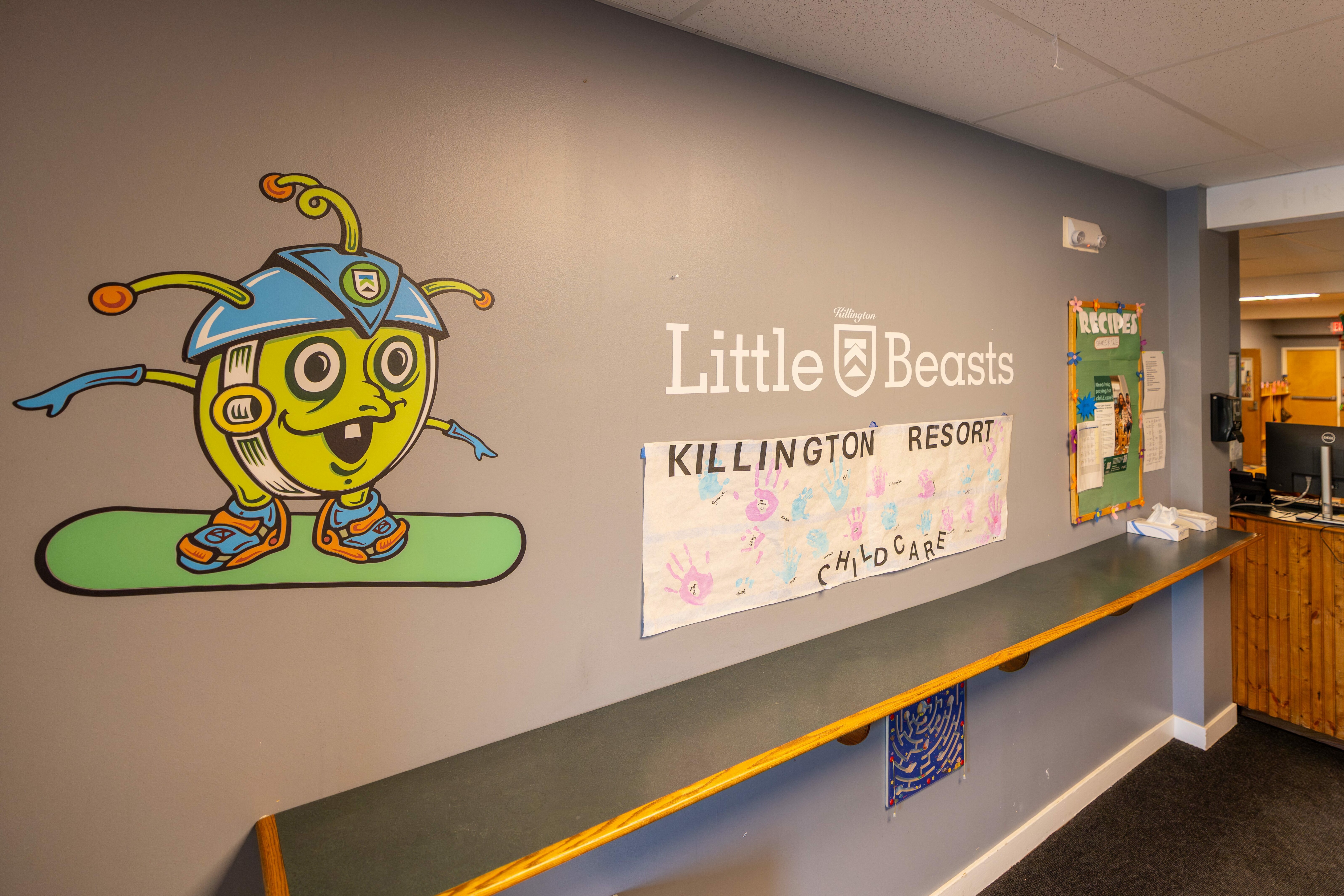 A colorful cartoon character on a wall in a childcare area with "Little Beasts" signage.