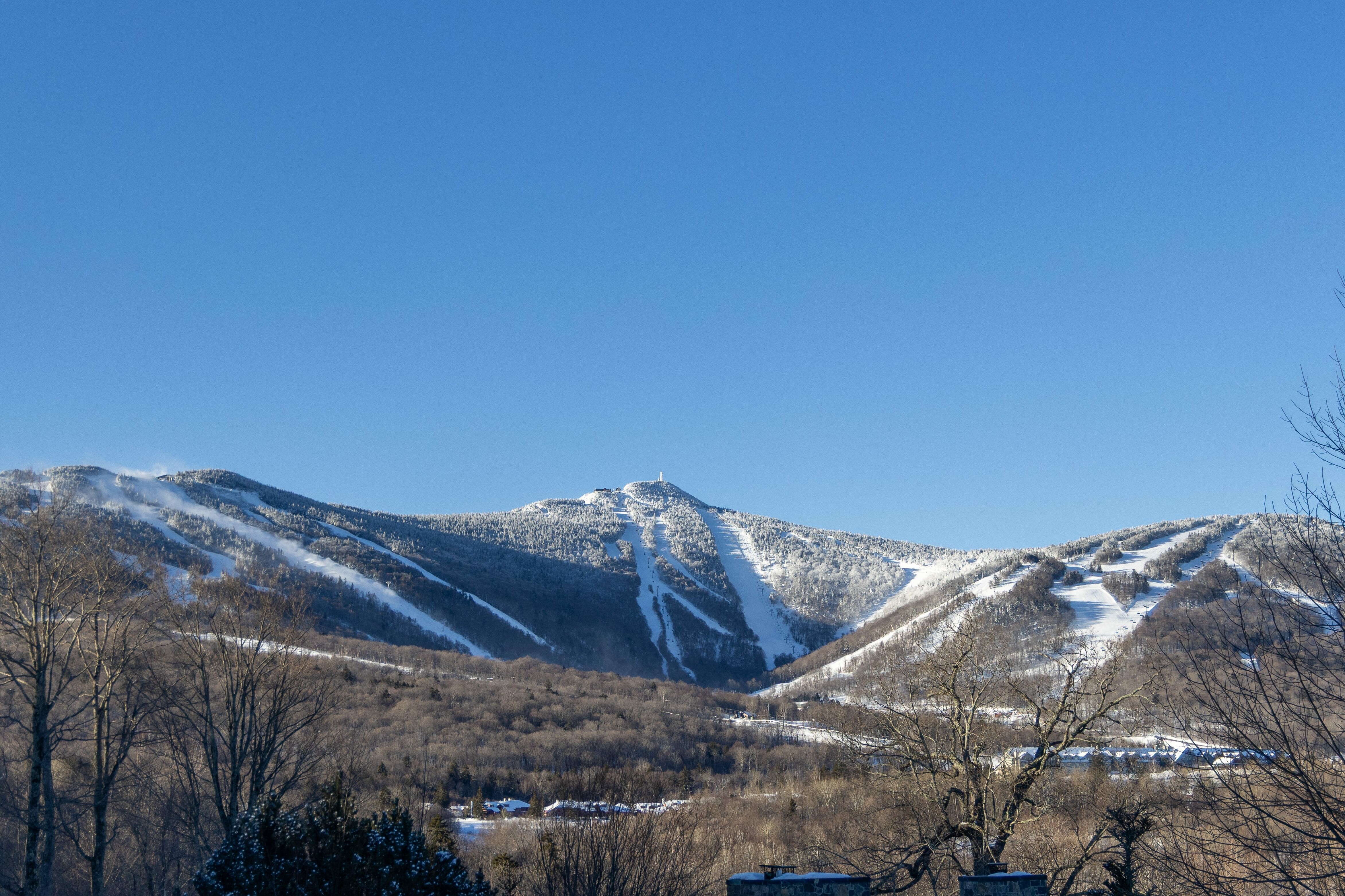 Snow-covered mountains under a clear blue sky.  Ski trails visible on the slopes.