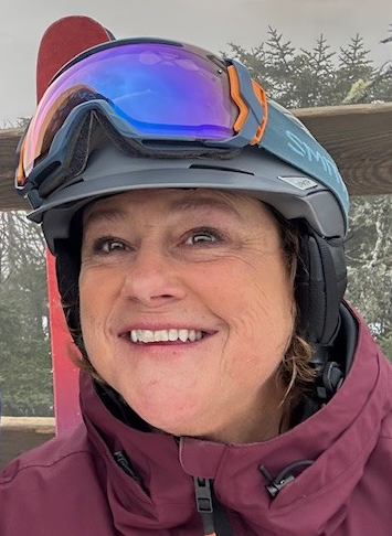 Smiling woman in ski gear with goggles.