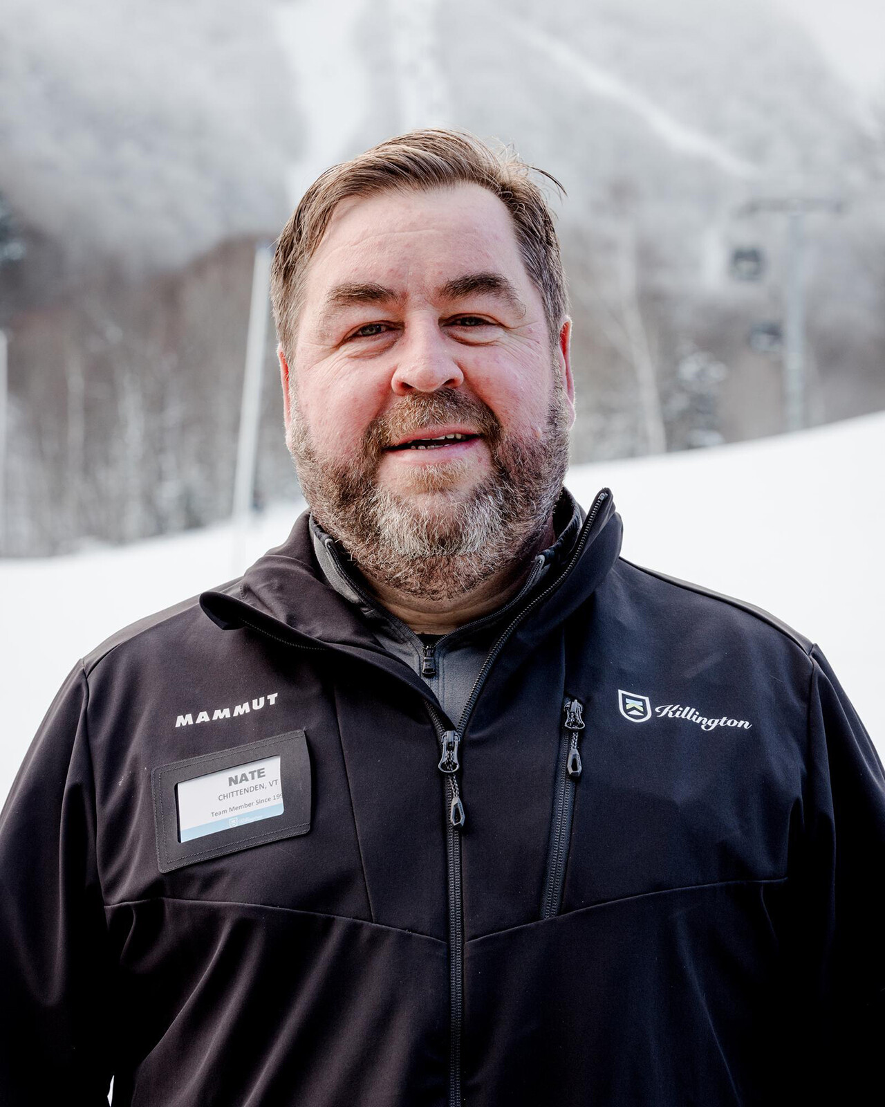 Smiling man in winter gear with a snowy background, identified as a team member at Killington.