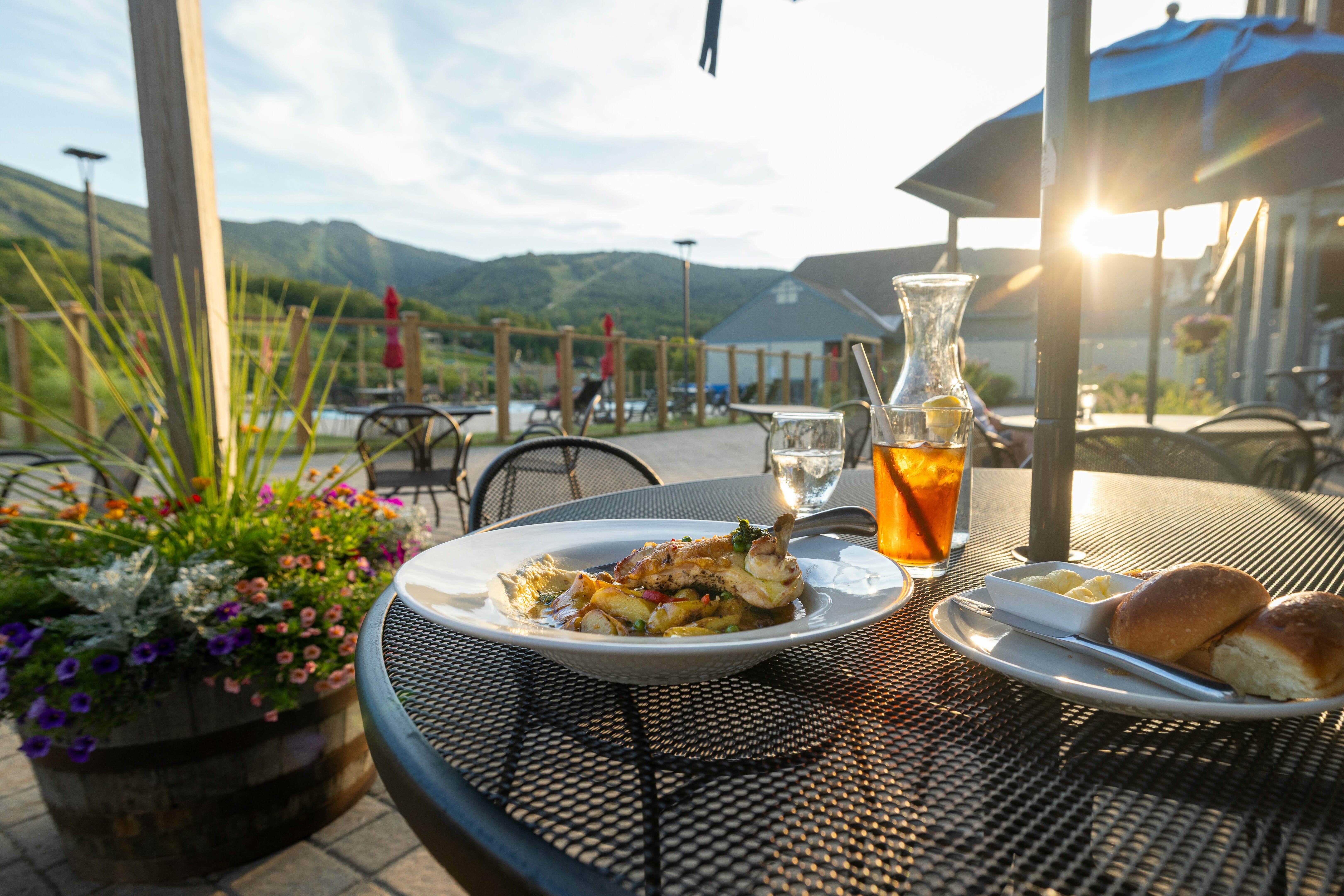 Dinner on a patio table with mountains in the background and sunlight shining.