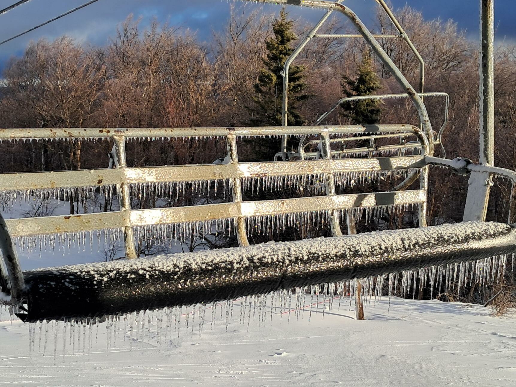 Icy ski lift with icicles, surrounded by snow and winter trees.