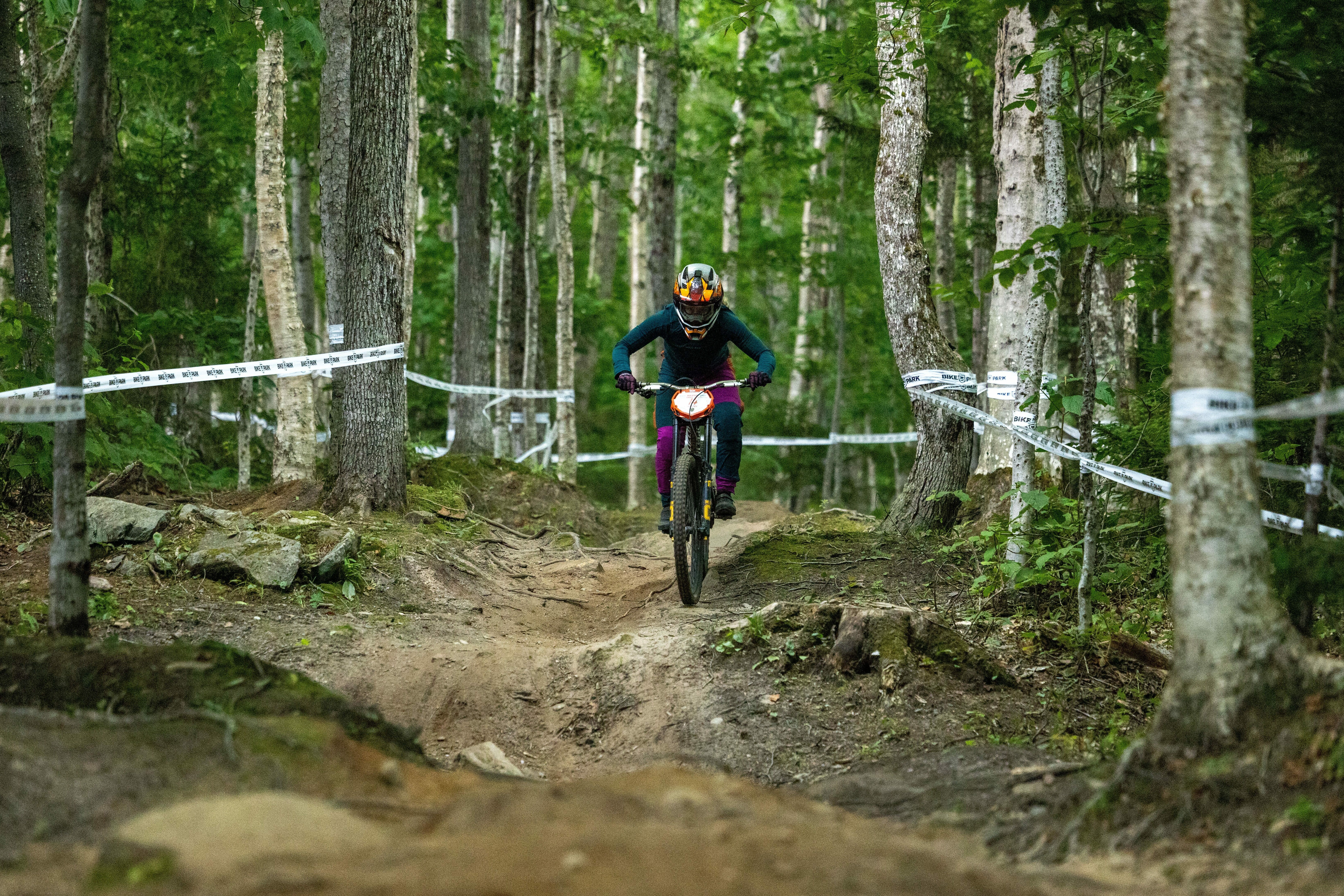 Mountain biker navigating a forest trail on a dirt path surrounded by trees.