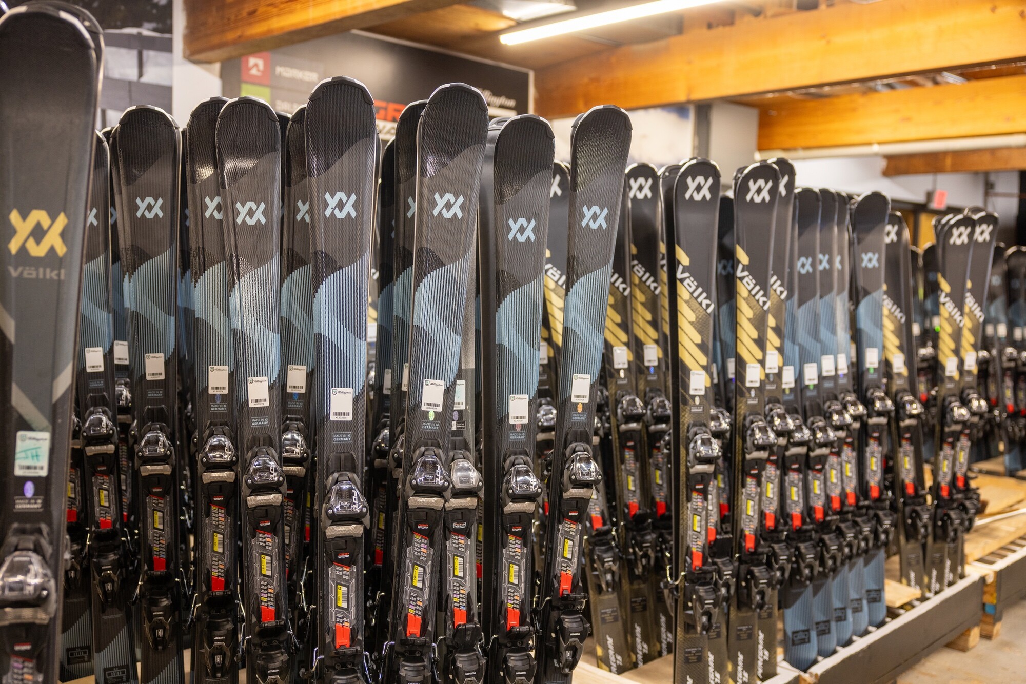 Rows of ski equipment displayed in a shop, featuring sleek black designs and bindings.