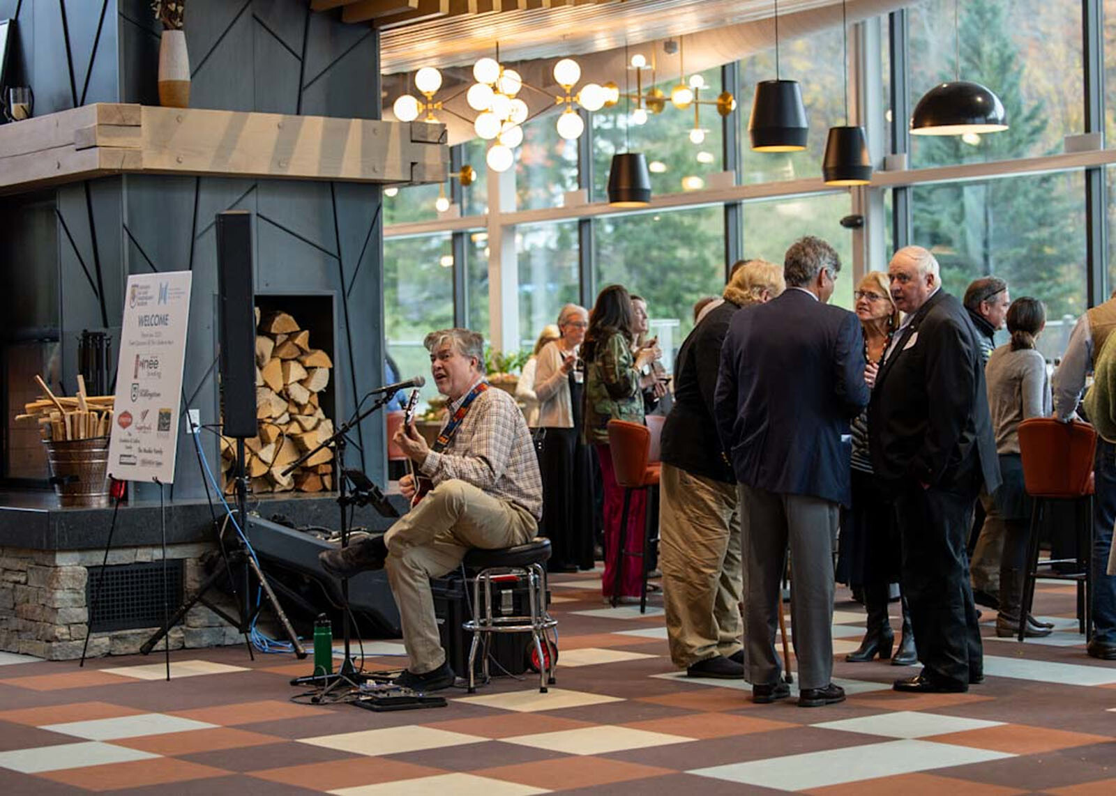 Musician performing in a lively gathering at a stylish venue with guests conversing.