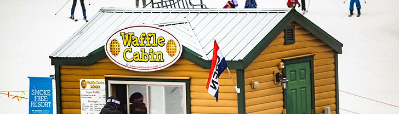Waffle Cabin at a ski resort with skiers in the background.