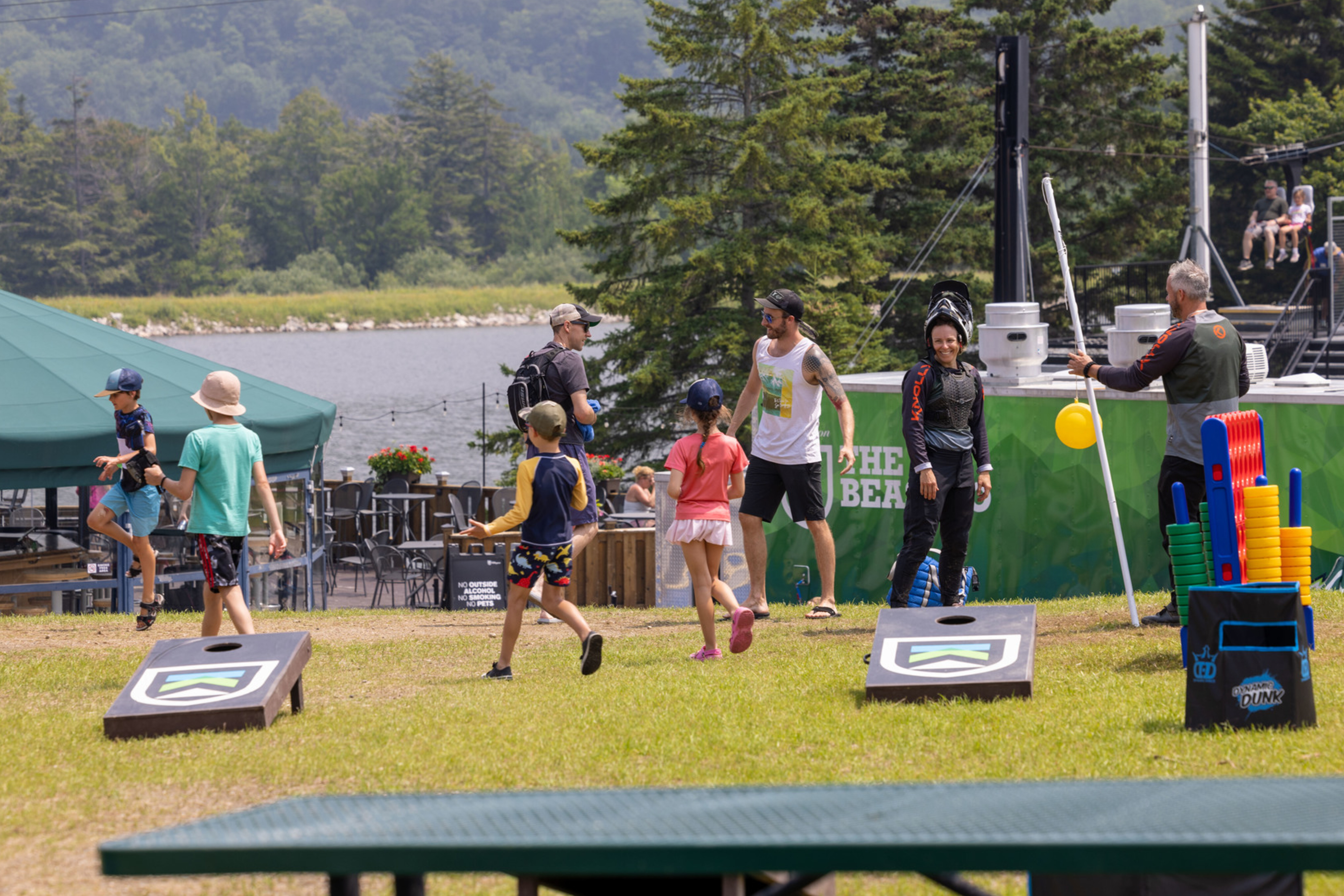 Children and adults enjoy outdoor activities by a lake on a sunny day.