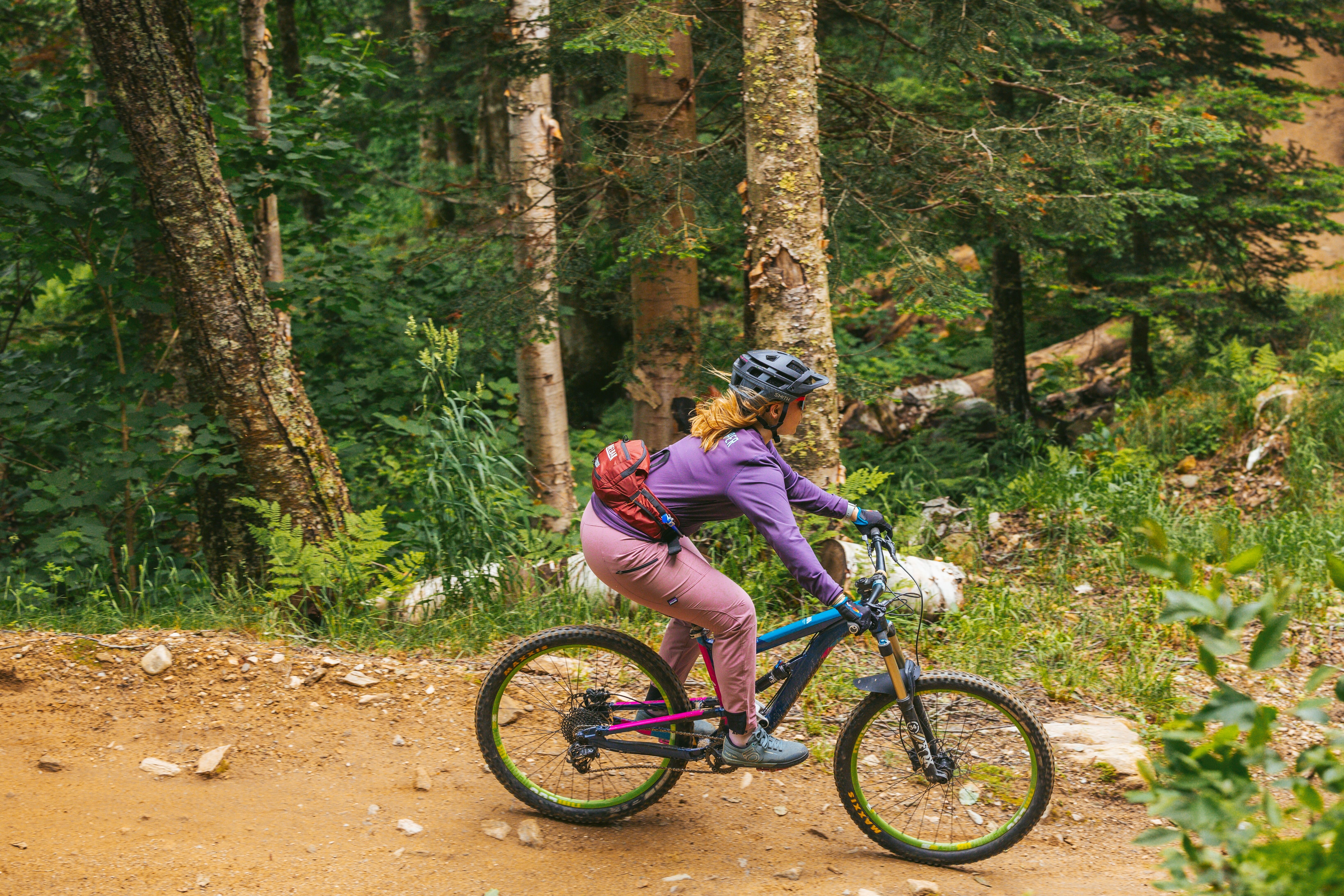 Person riding a mountain bike on a dirt trail surrounded by trees.