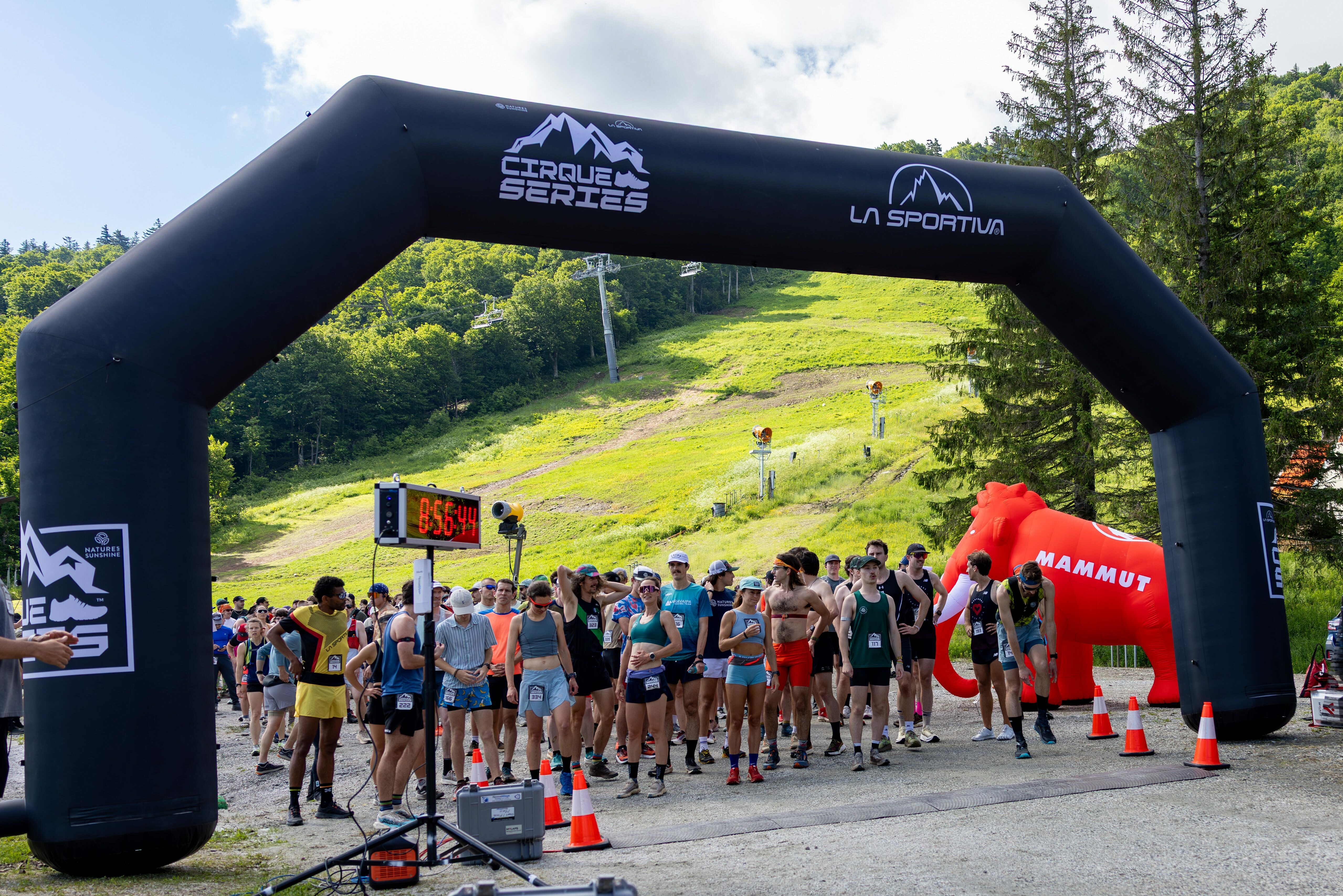 Runners gather at the starting line beneath a large inflatable archway