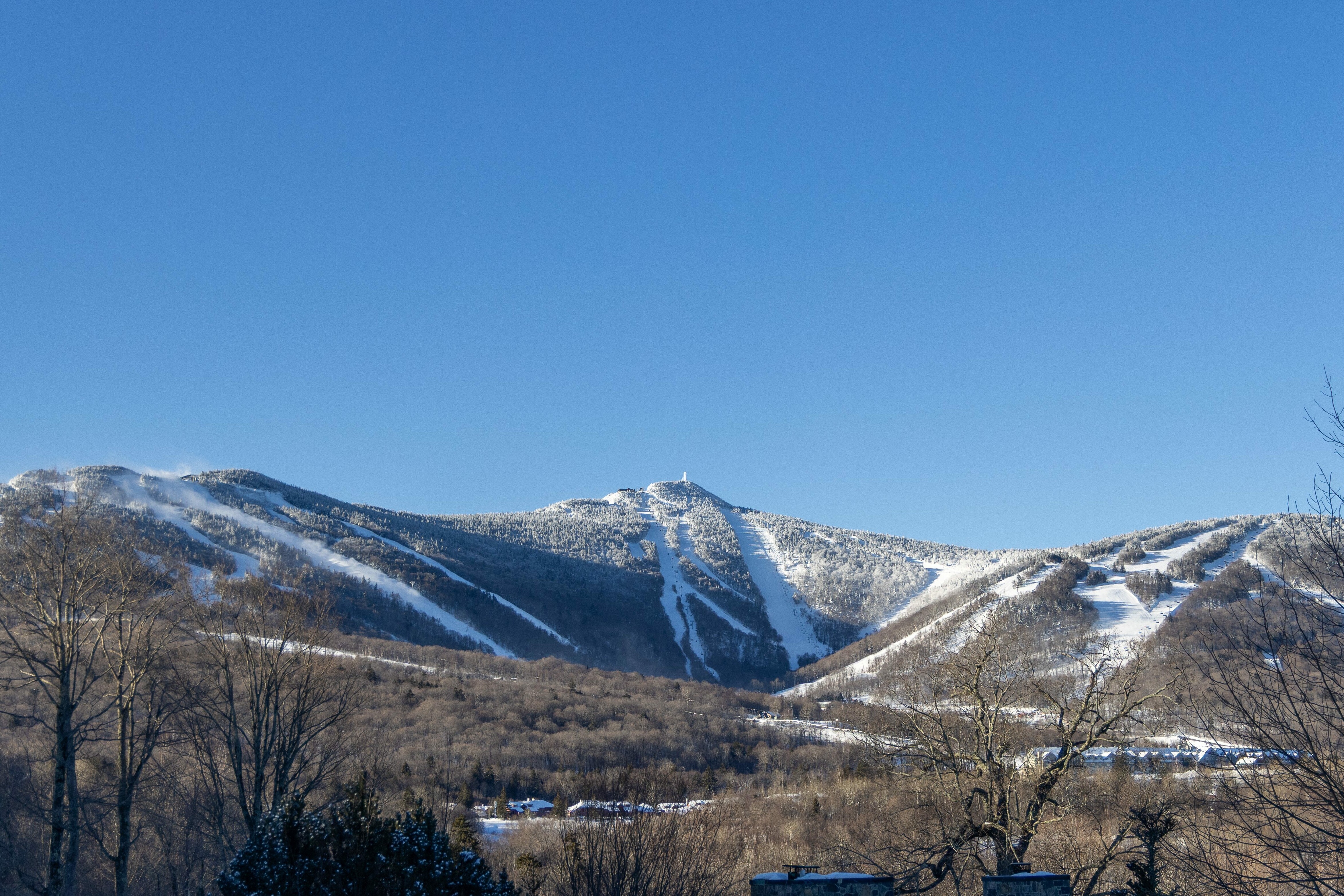 Snow-covered mountains under a clear blue sky, with ski trails visible.