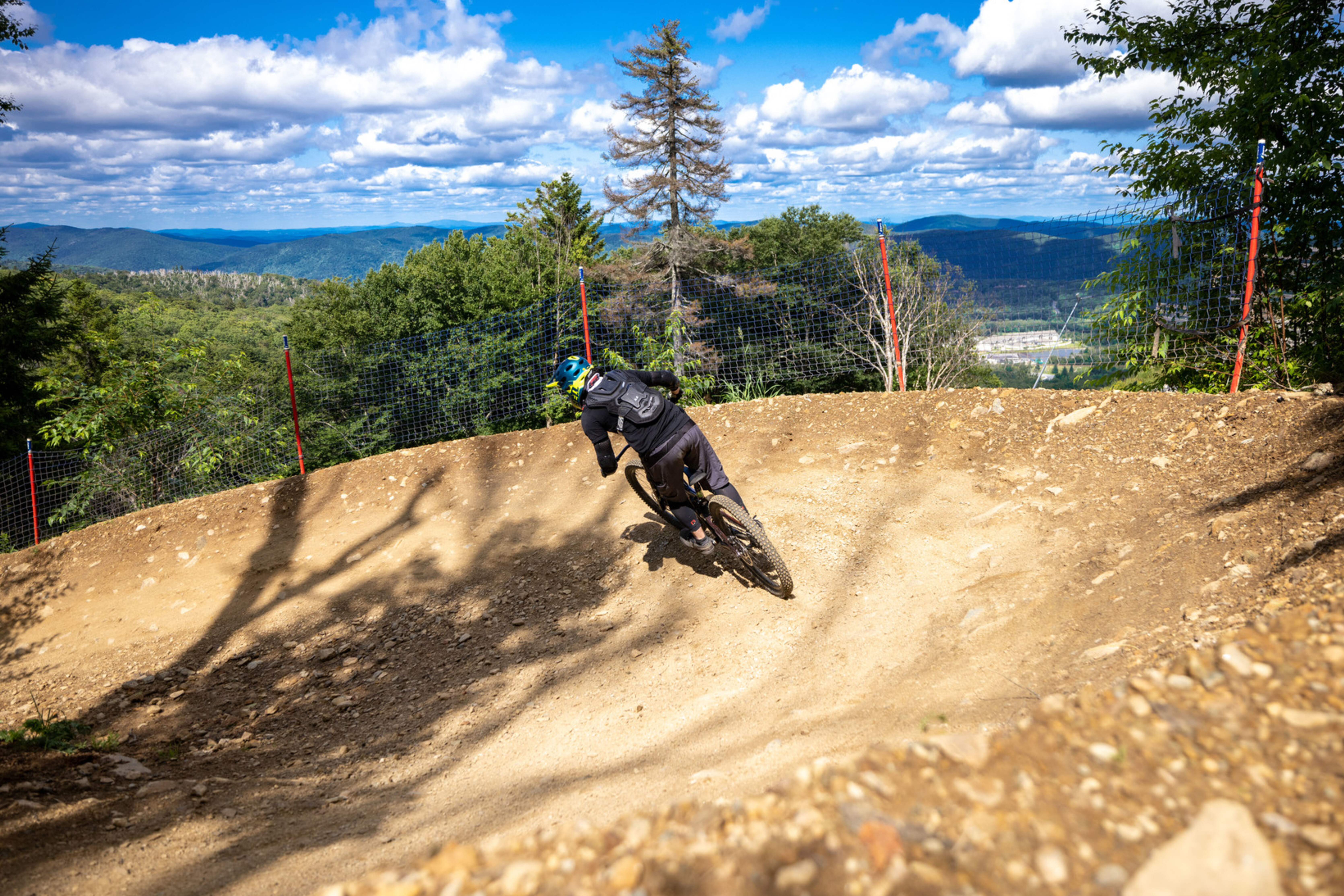 Mountain biker navigating a dirt trail with a scenic landscape in the background.